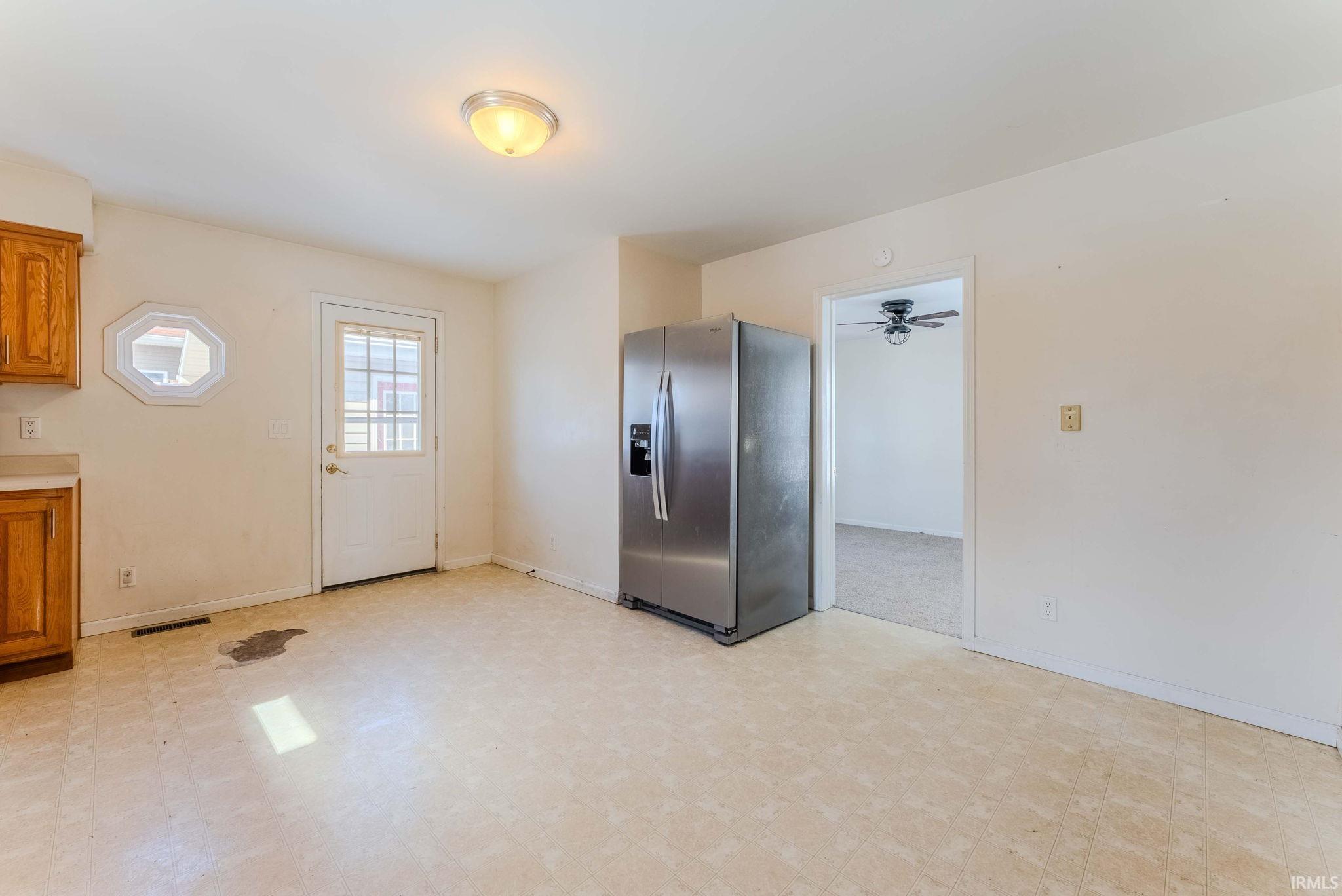 Kitchen featuring stainless steel refrigerator with ice dispenser, light floors, wood finish cabinetry, and light countertops