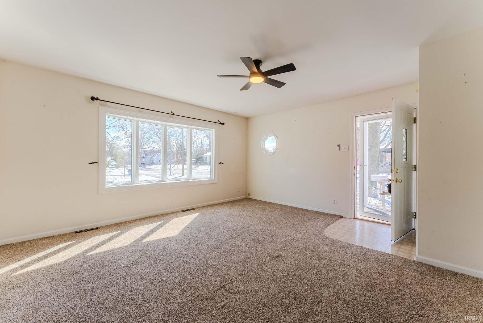 Empty room with ceiling fan and light carpet