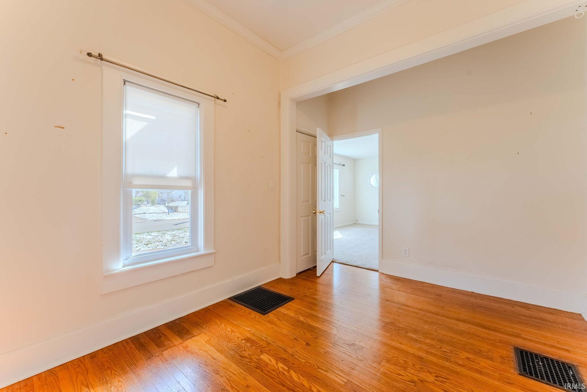 Empty room with light wood-style floors and crown molding
