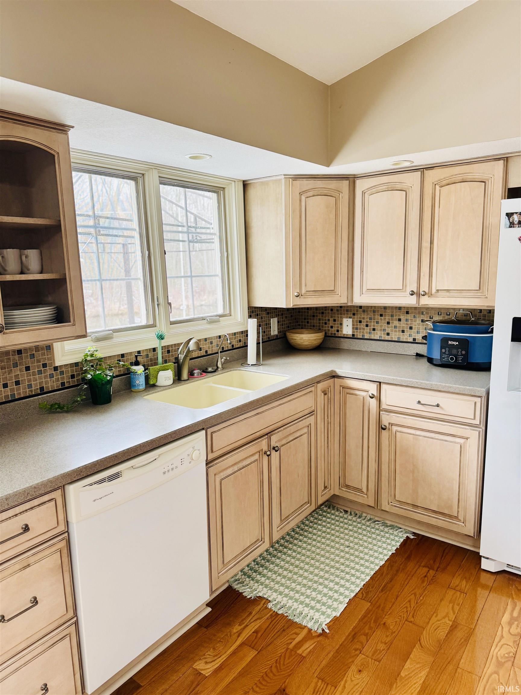 Kitchen featuring light wood finish cabinets, white appliances, light wood-style flooring, and light countertops