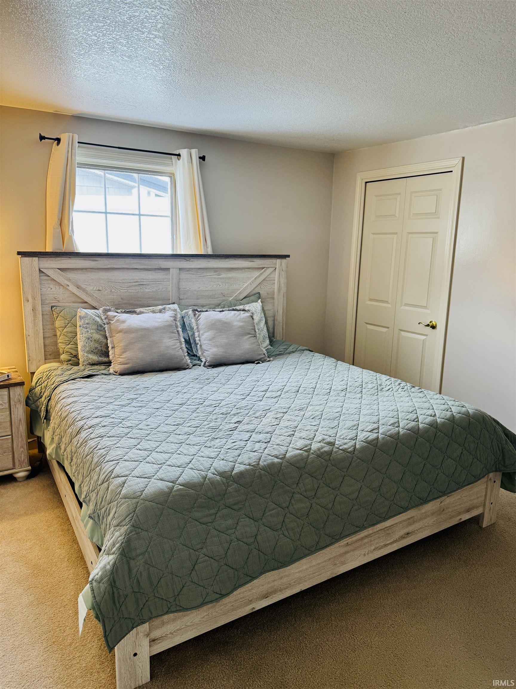 Bedroom with carpet, a textured ceiling, and a closet