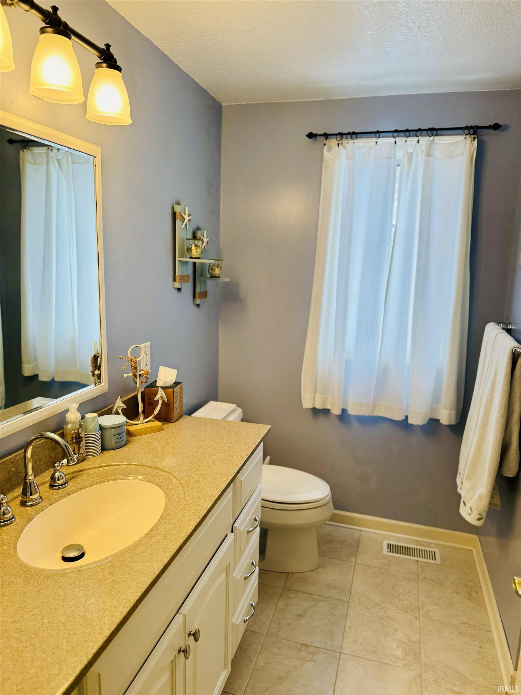 Bathroom with vanity, a textured ceiling, and light tile patterned flooring