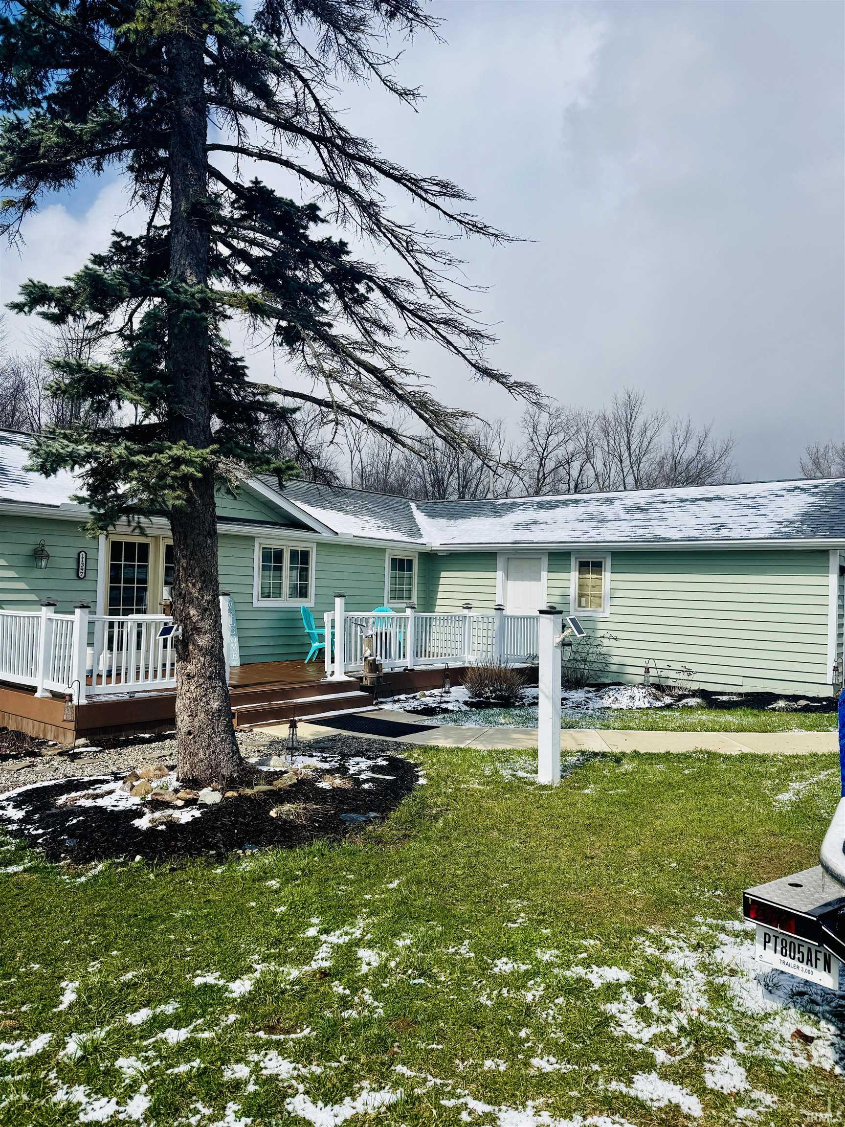 Snow covered property with a deck and a yard