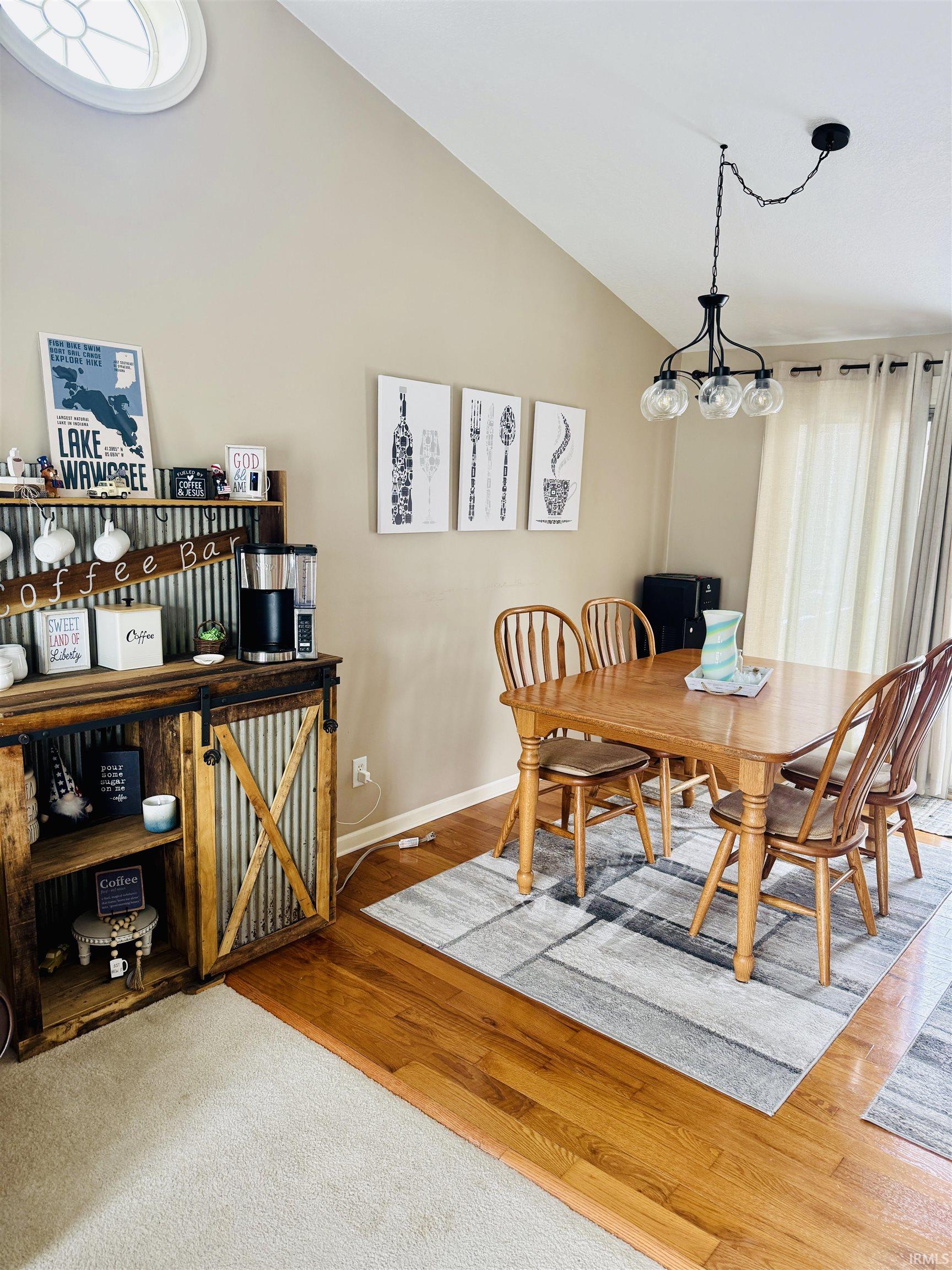 Dining area featuring light wood-style floors, vaulted ceiling, and suspended lighting