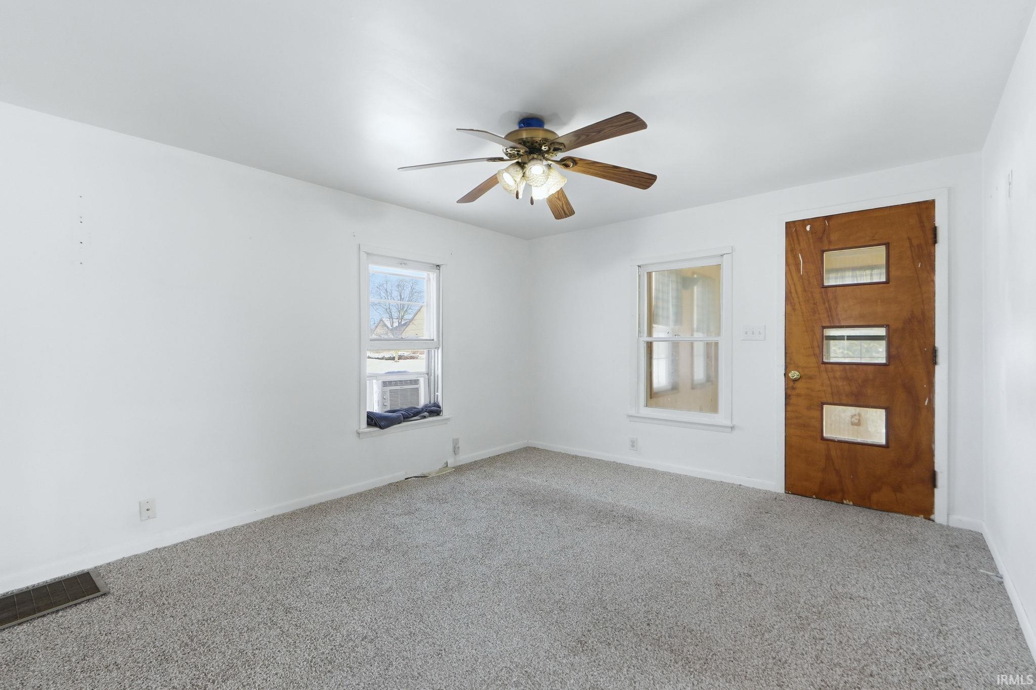 Carpeted spare room featuring a ceiling fan and baseboards
