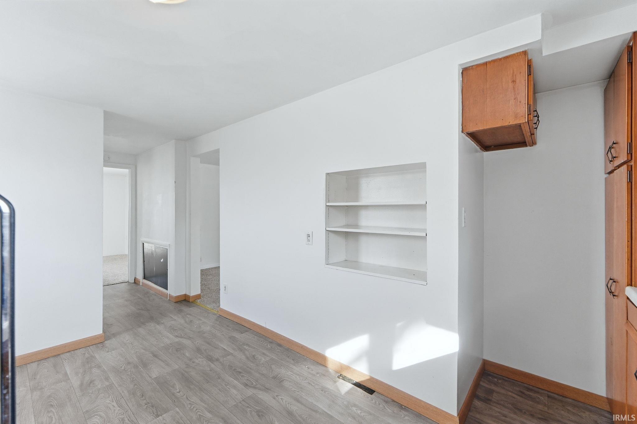 Empty room featuring built in shelves and light wood finished floors