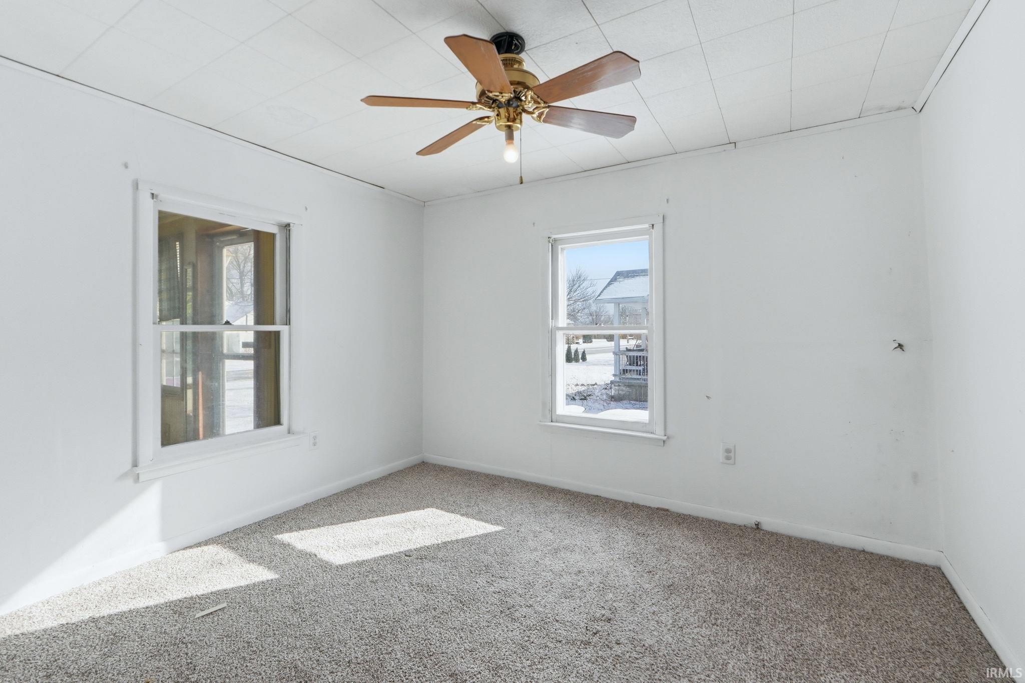Empty room featuring a ceiling fan and carpet