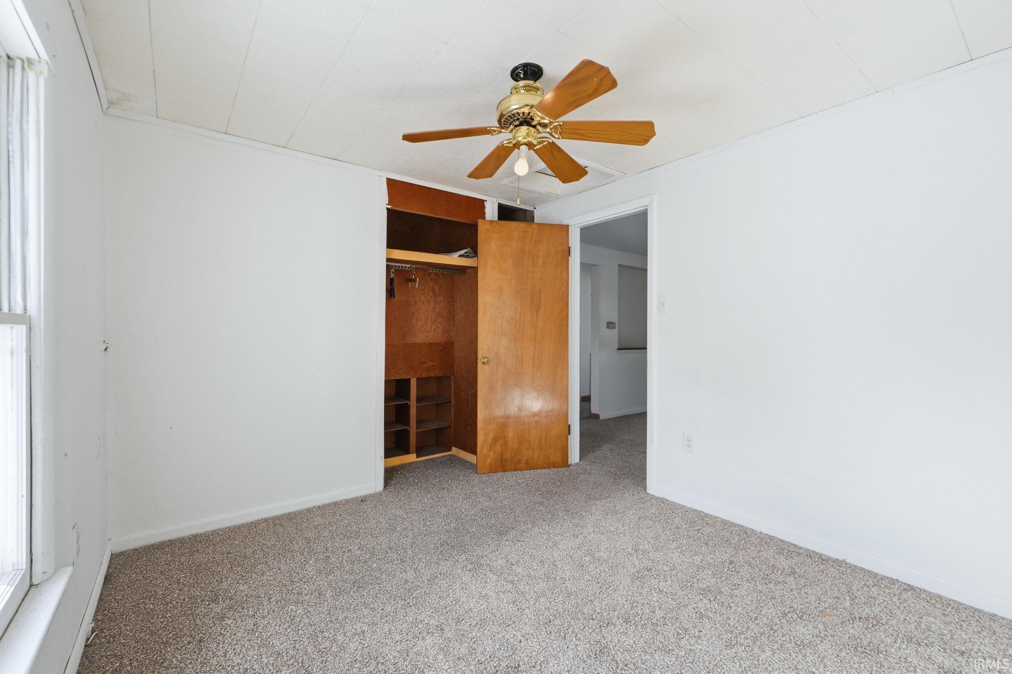 Unfurnished bedroom featuring carpet flooring, ceiling fan, and a closet
