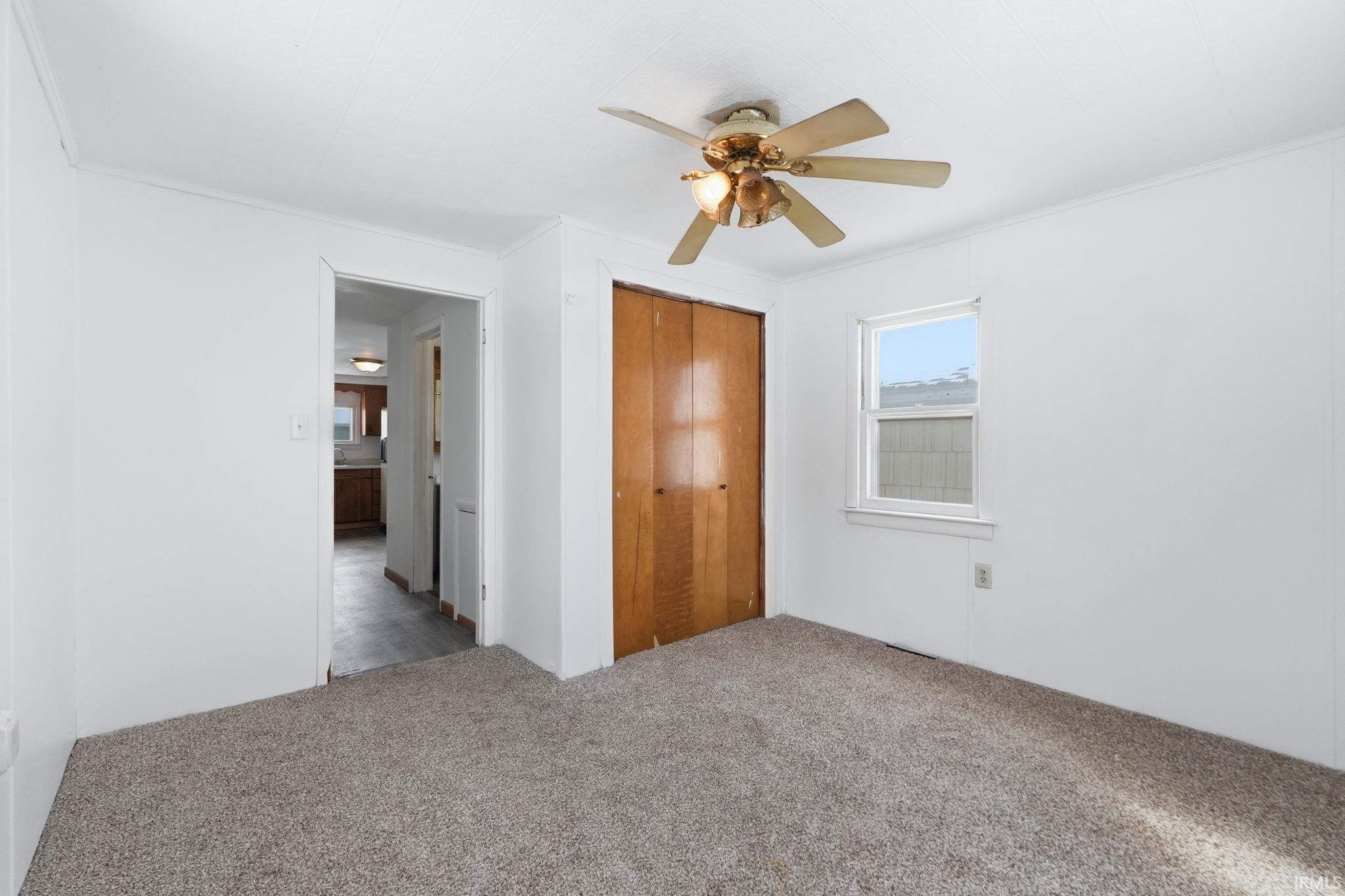 Unfurnished bedroom with carpet flooring, a closet, and a ceiling fan
