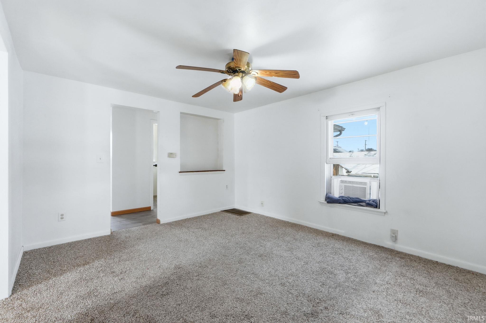 Carpeted spare room featuring baseboards and a ceiling fan