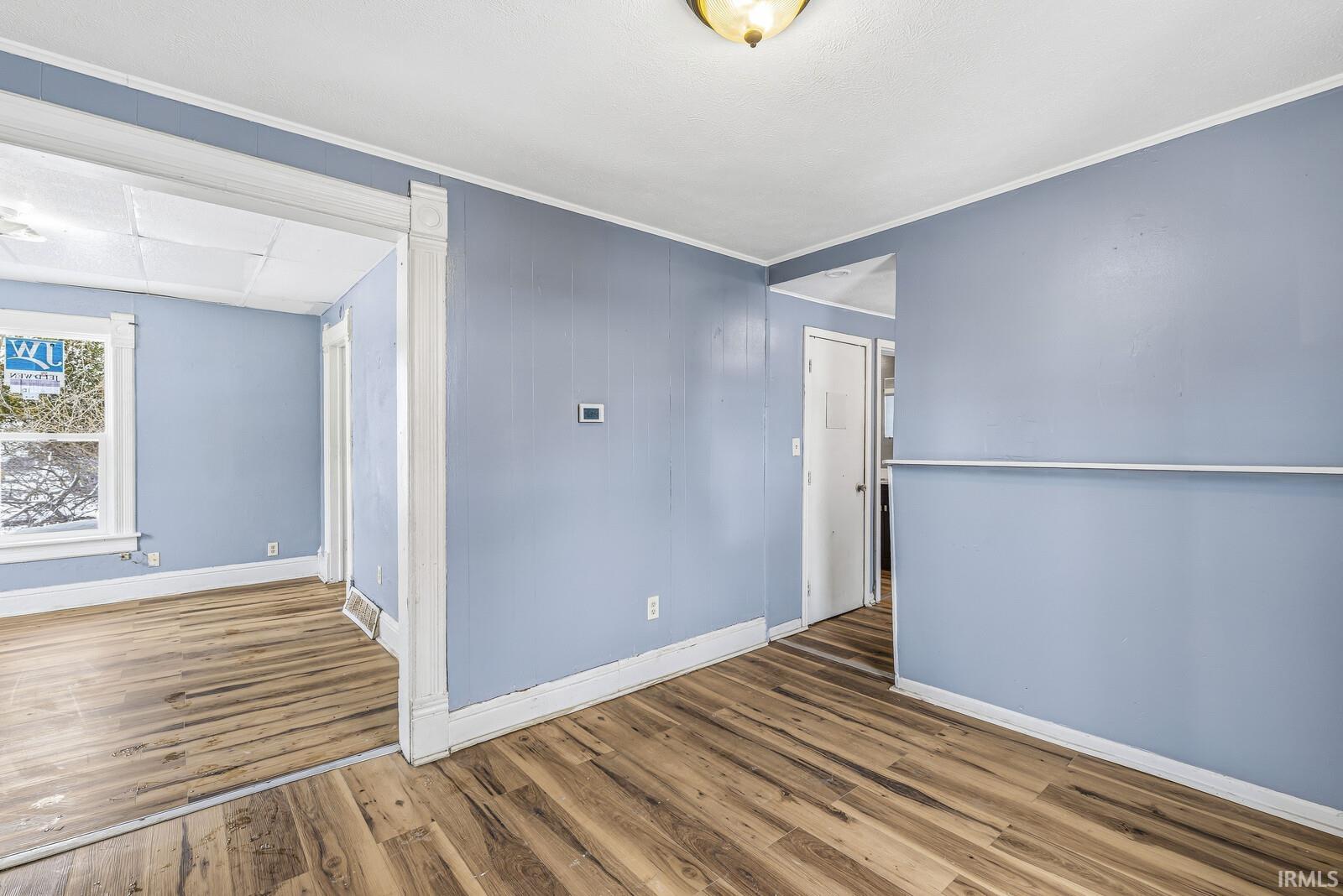 Spare room with wood finished floors and crown molding