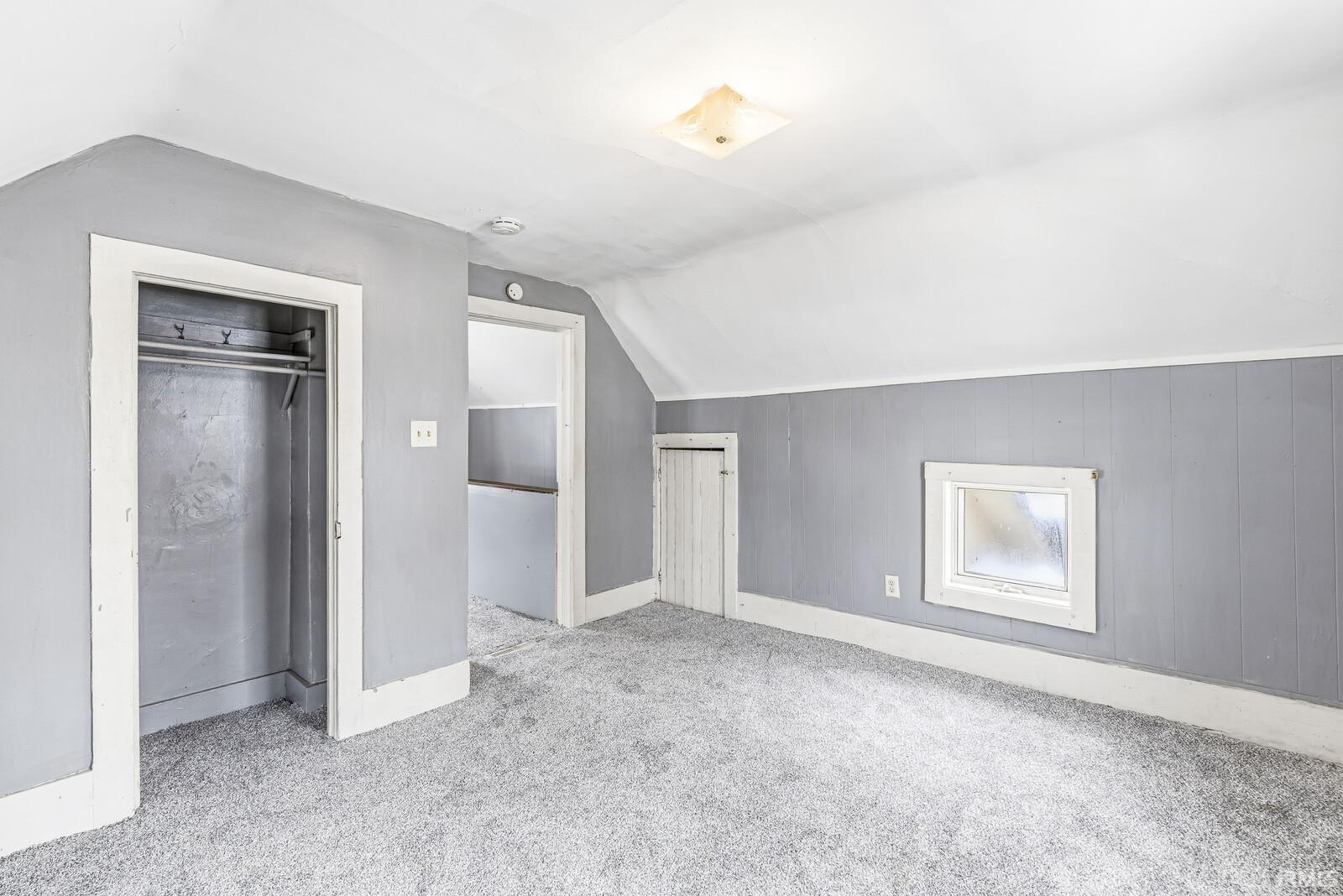 Bonus room featuring lofted ceiling, carpet, and wooden walls