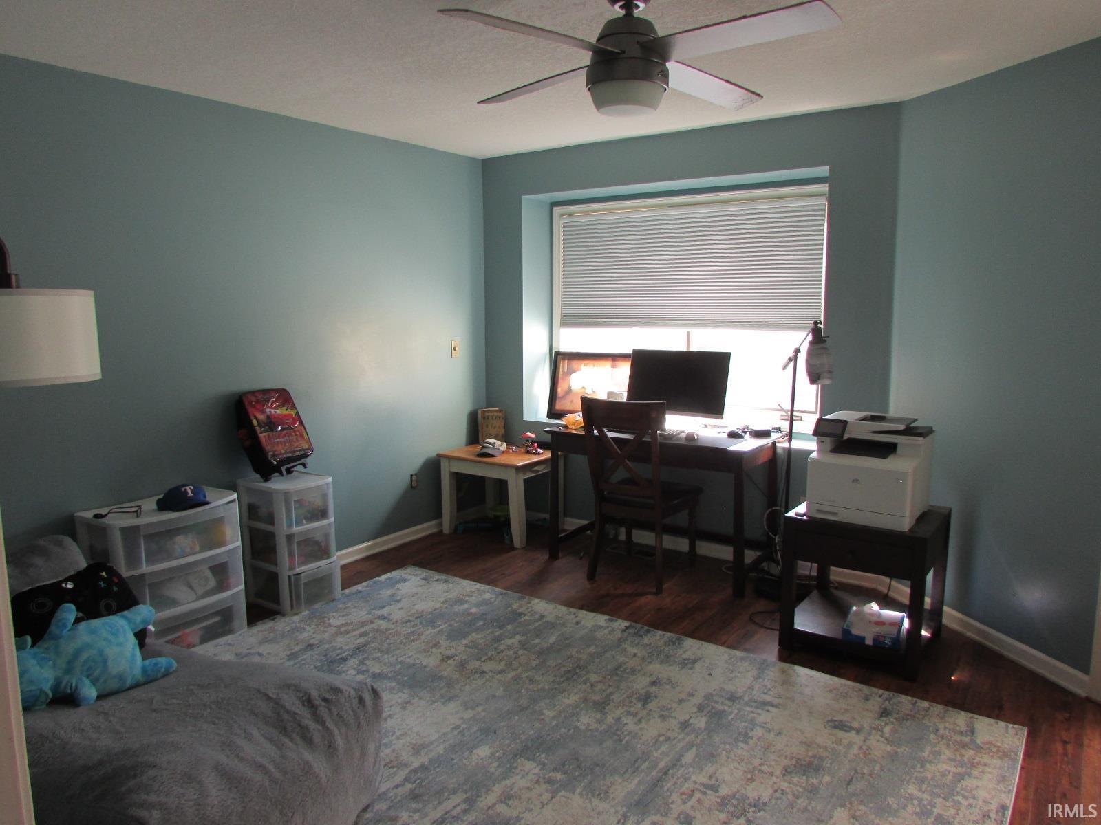 Home office with dark wood-style floors and a ceiling fan