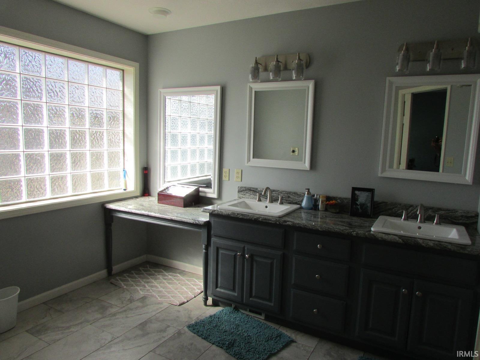 Full bathroom featuring double vanity and light marble finish flooring