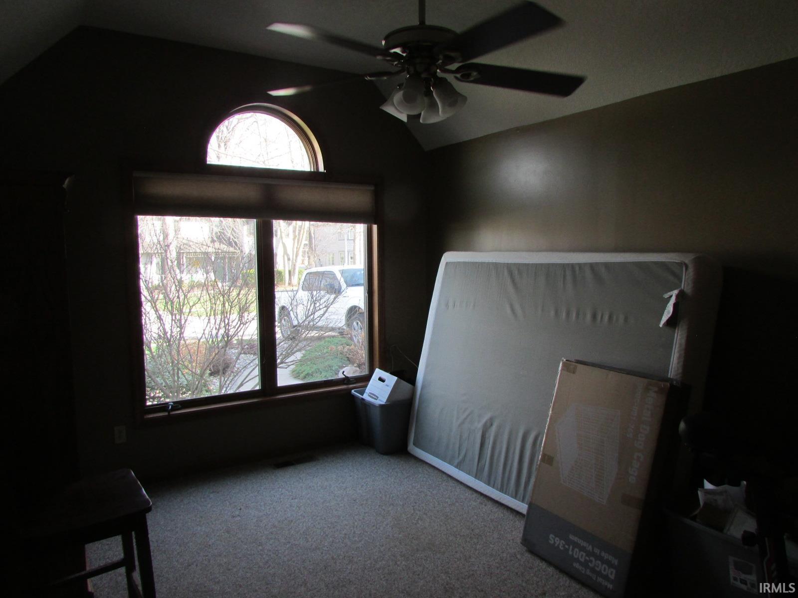 Unfurnished bedroom with a ceiling fan, light carpet, and vaulted ceiling