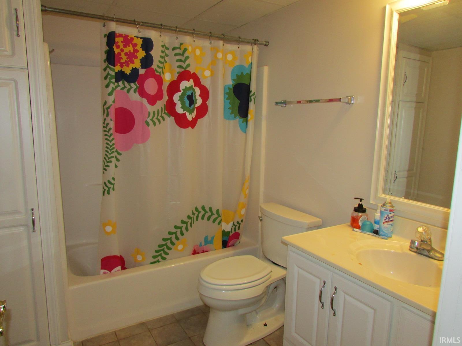 Bathroom featuring vanity, shower / bathtub combination with curtain, and light tile patterned floors