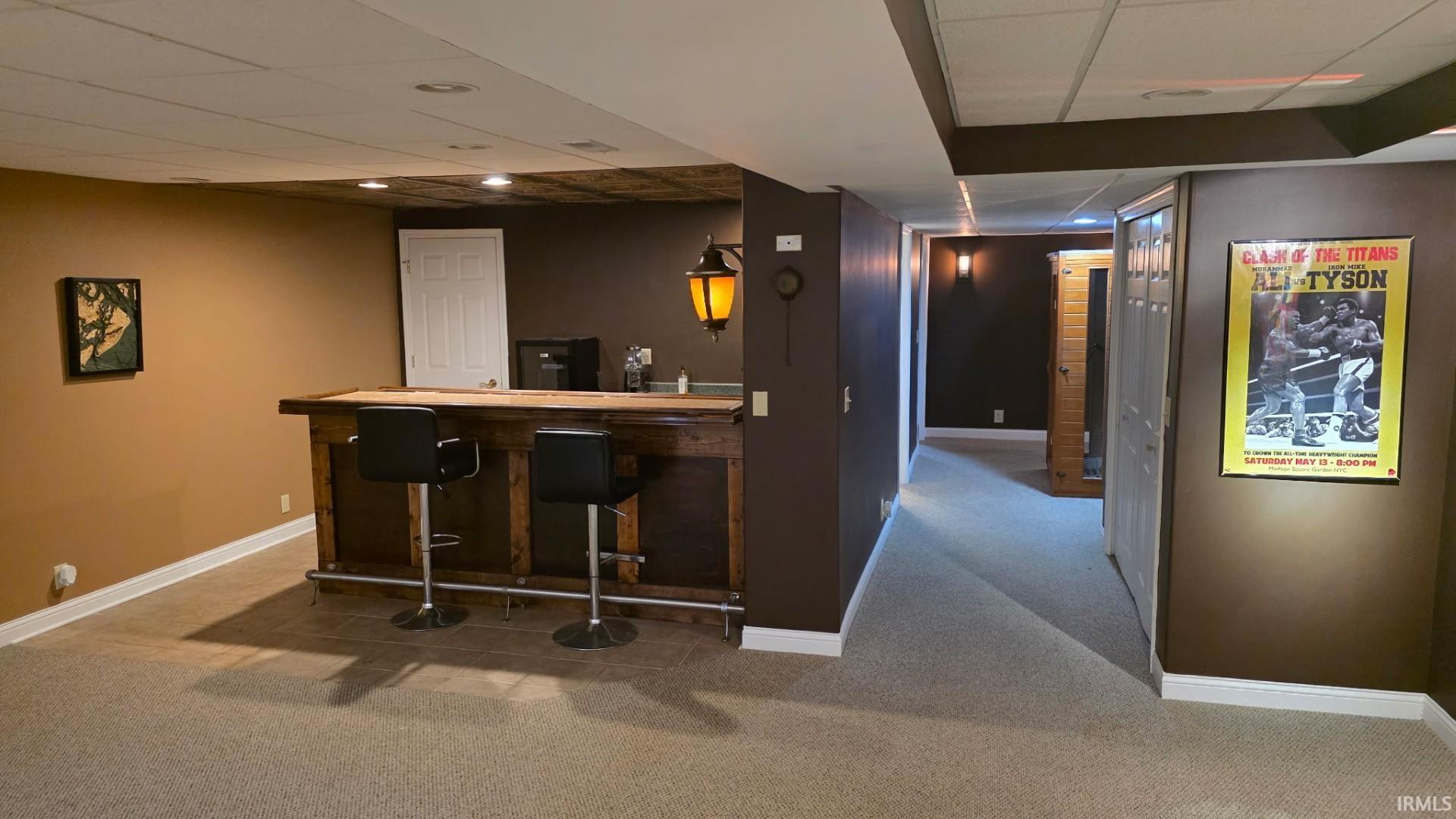 Indoor dry bar featuring light colored carpet, a drop ceiling, and butcher block counters