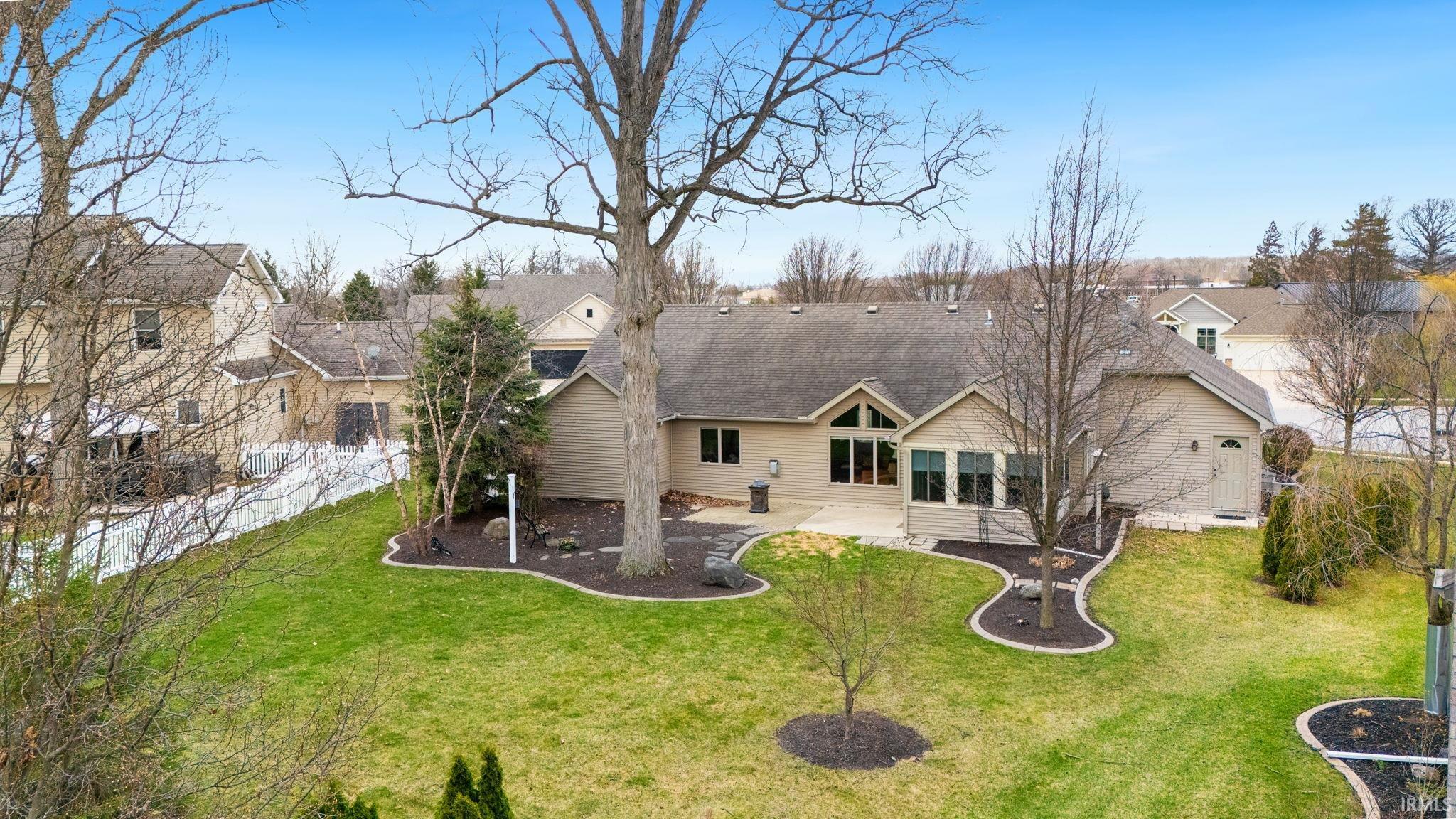 Back of property featuring a patio area, a lawn, a sunroom, and roof with shingles