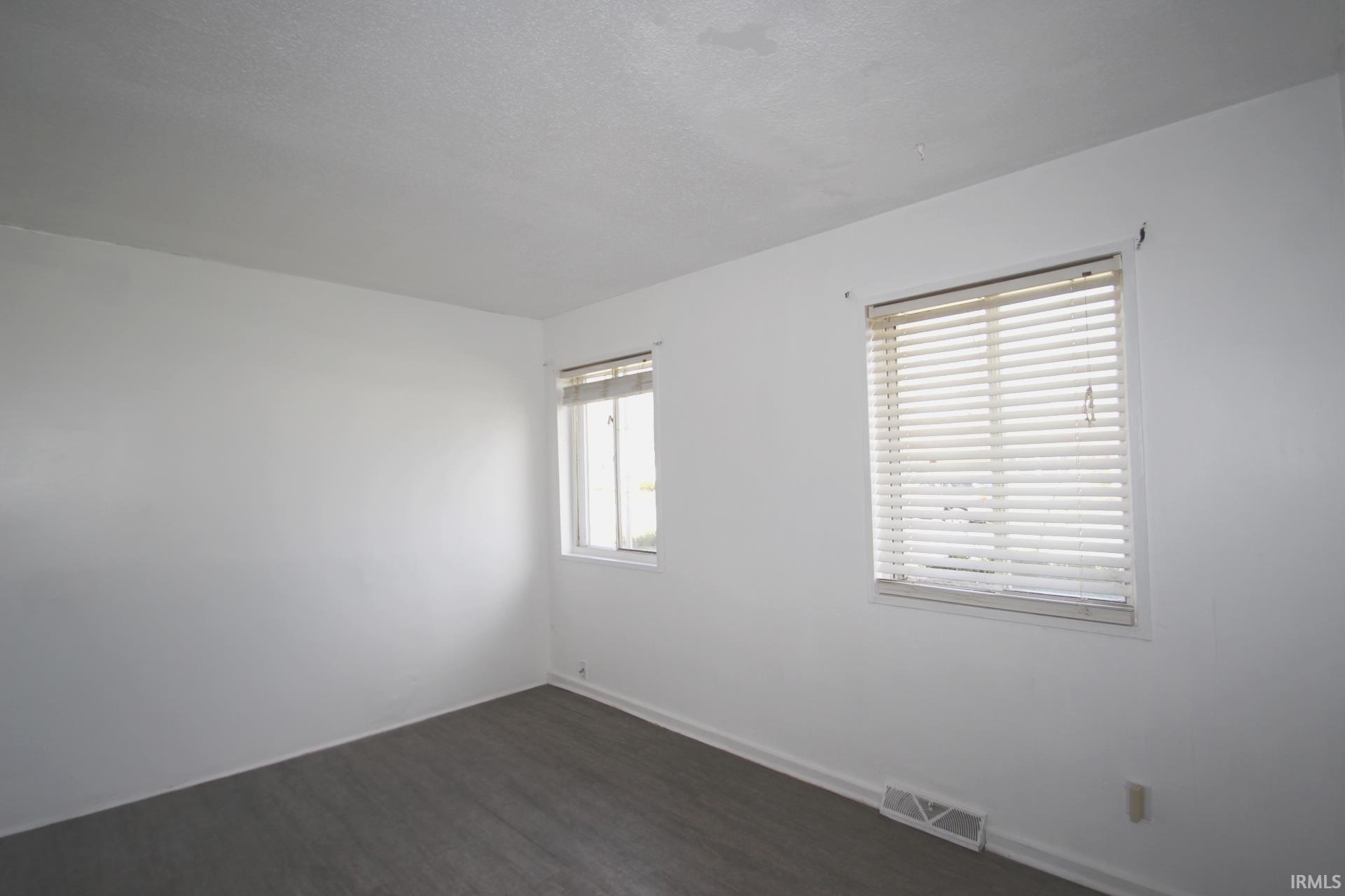 Empty room featuring dark wood finished floors and baseboards