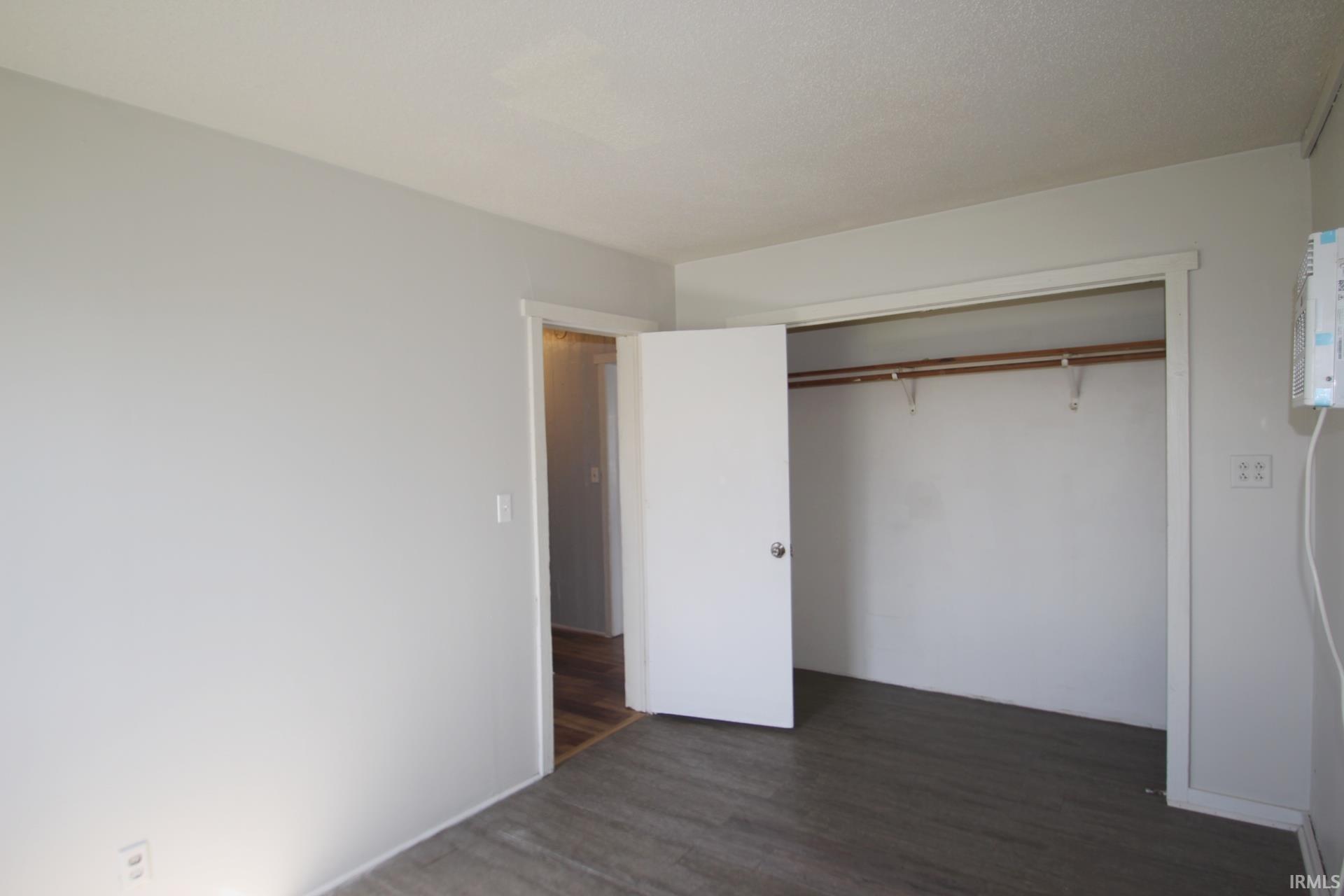 Unfurnished bedroom featuring dark wood-style floors and a closet