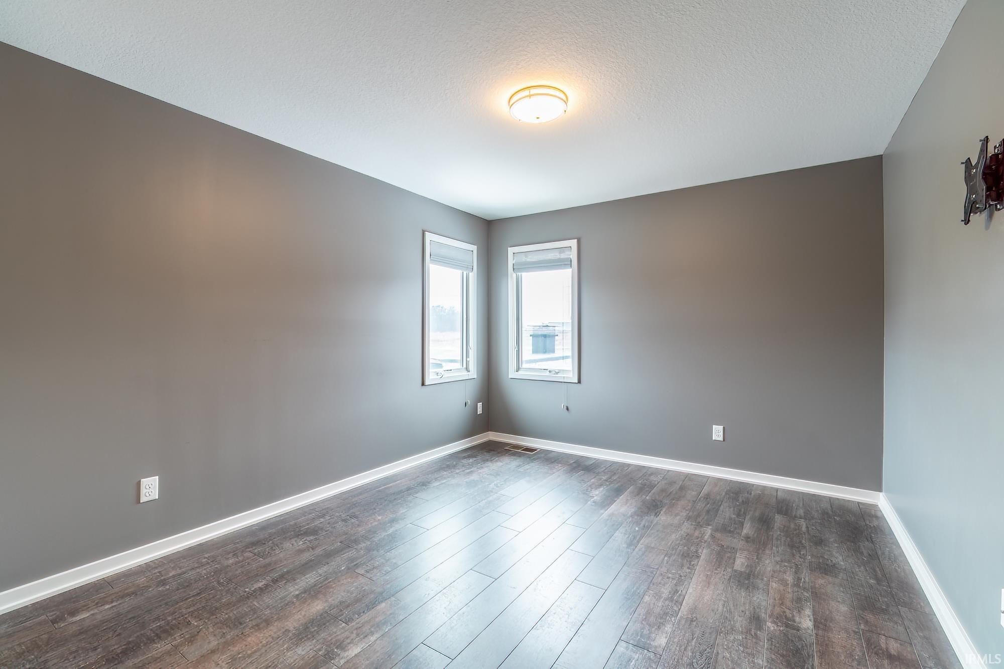 Empty room with dark wood-style flooring and a textured ceiling
