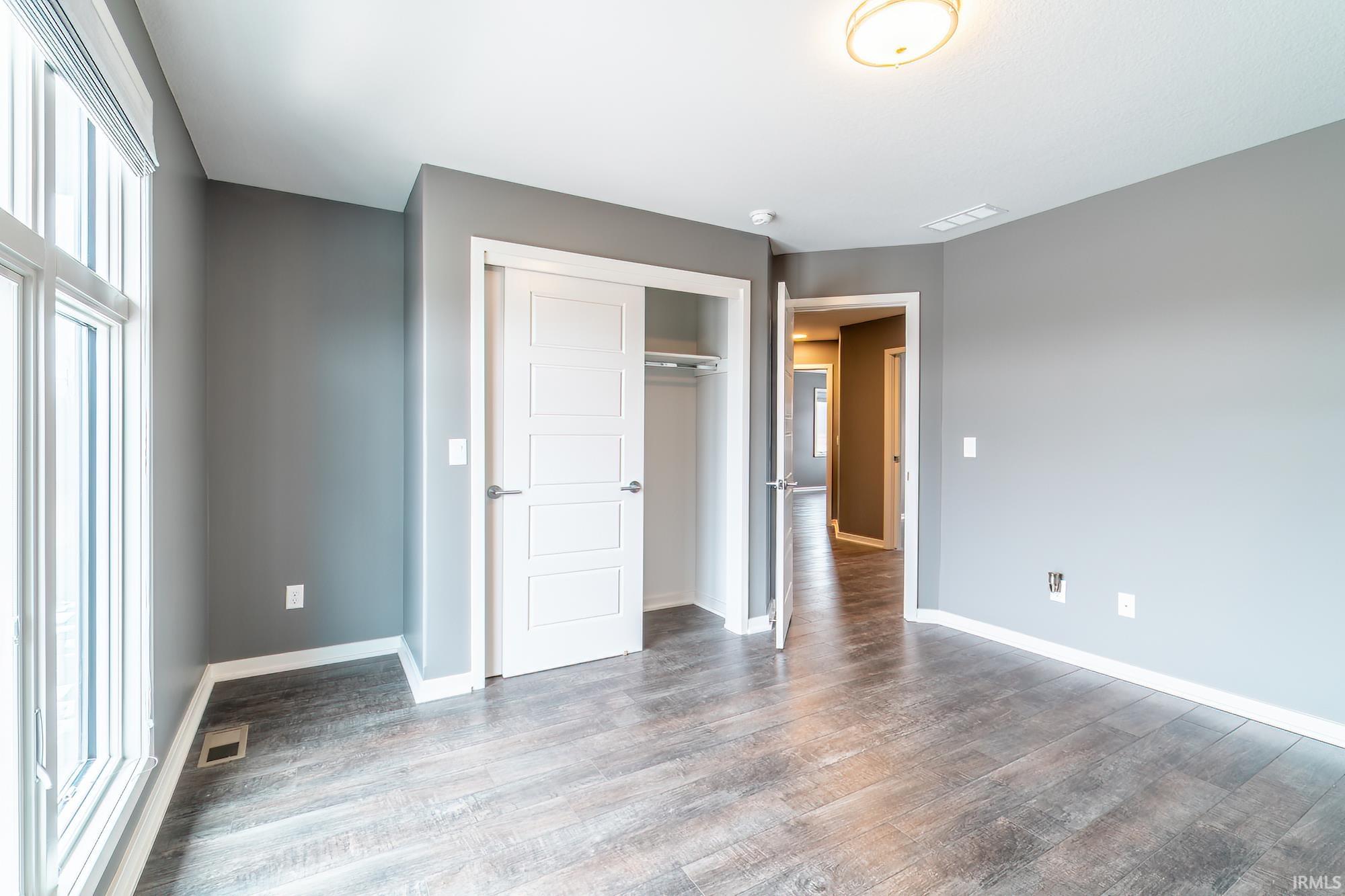 Unfurnished bedroom featuring a closet and dark wood finished floors
