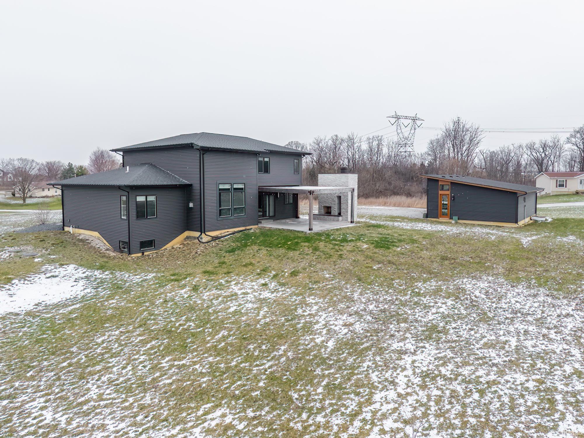 Snow covered back of property featuring a patio and an outbuilding