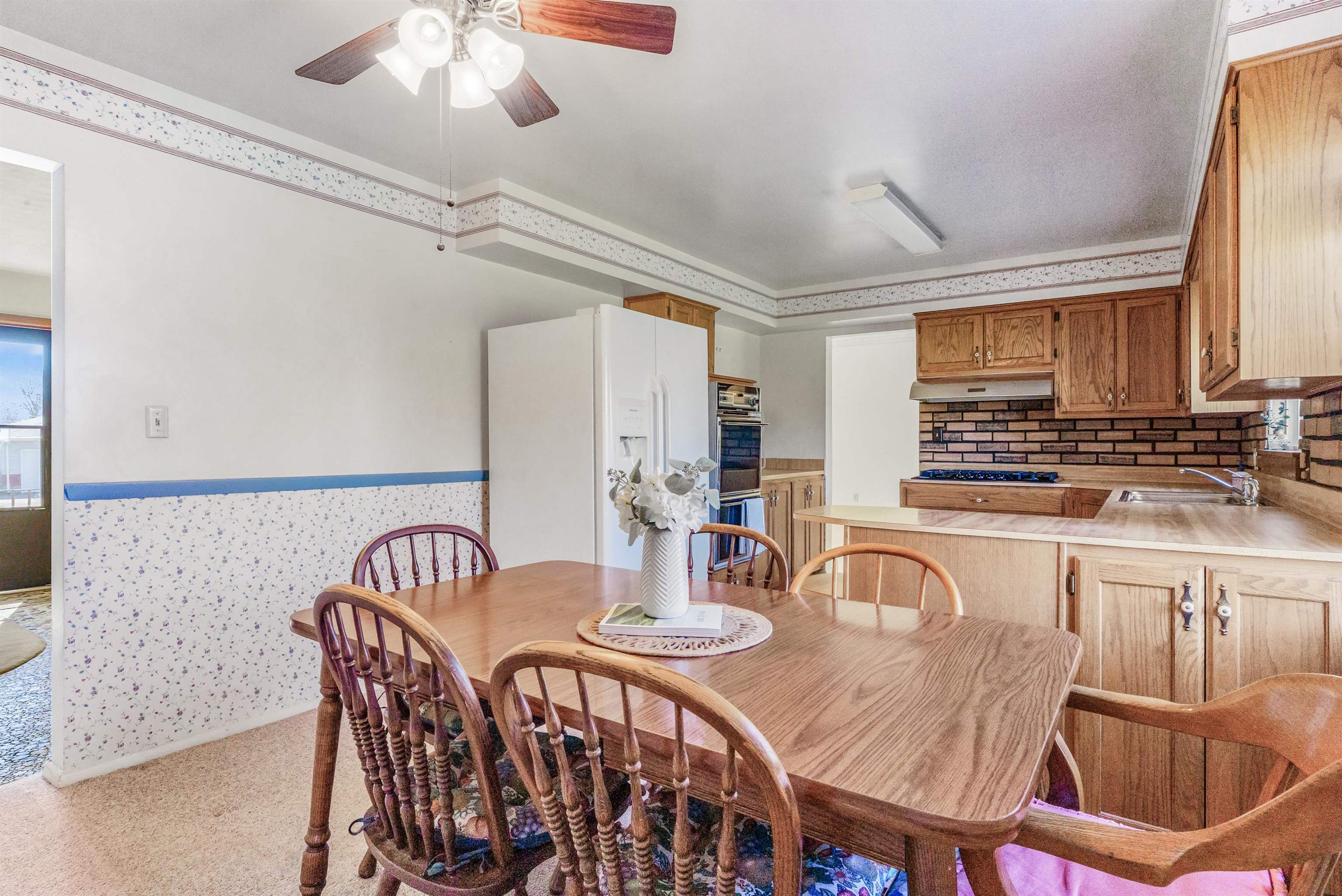 Dining area featuring a wainscoted wall, a ceiling fan, wallpapered walls, and ornamental molding