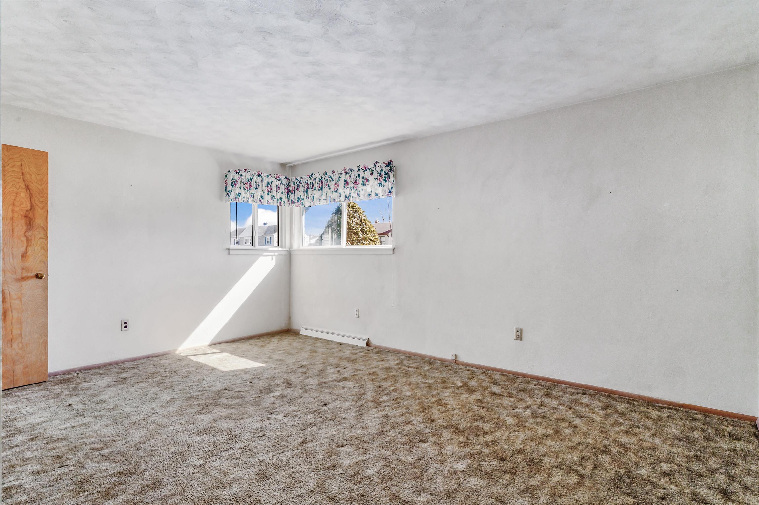 Carpeted empty room featuring a textured ceiling and baseboards