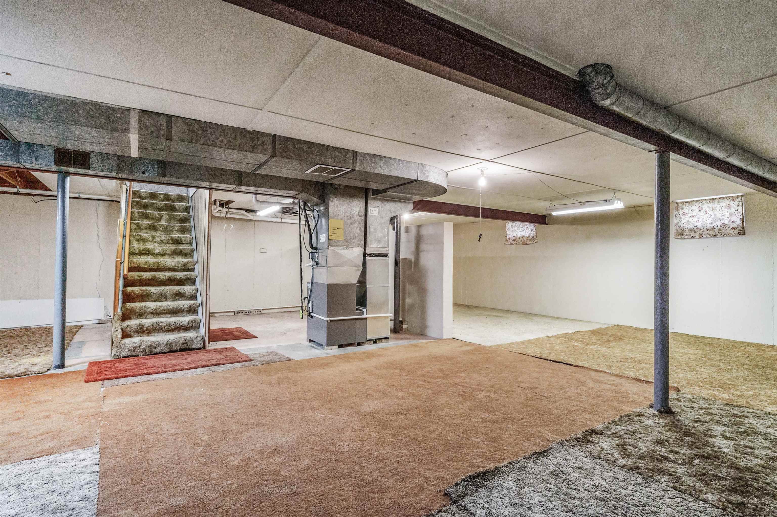 Finished basement featuring stairway and heating unit