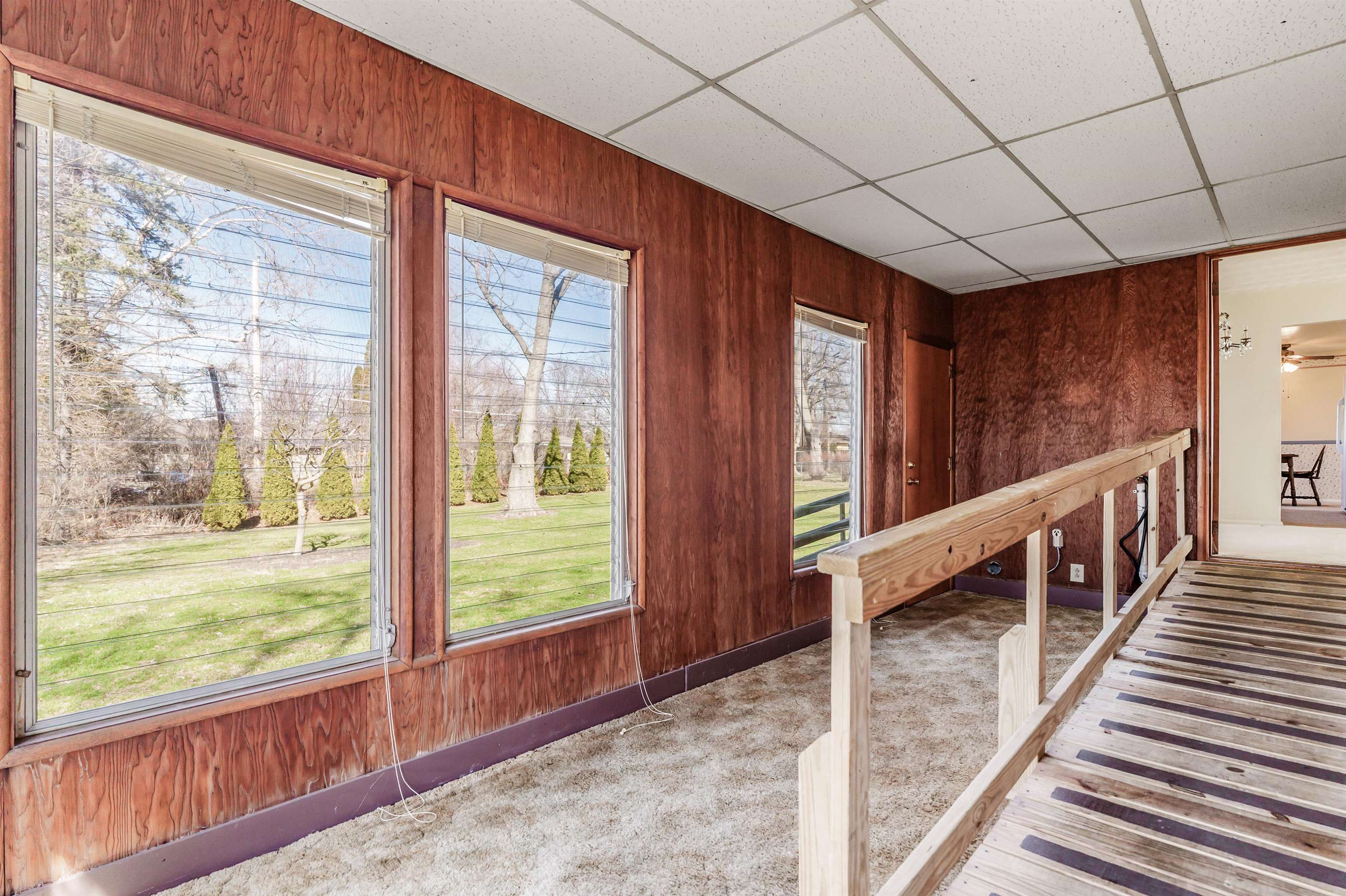 Interior space featuring a drop ceiling, carpet, and wooden walls