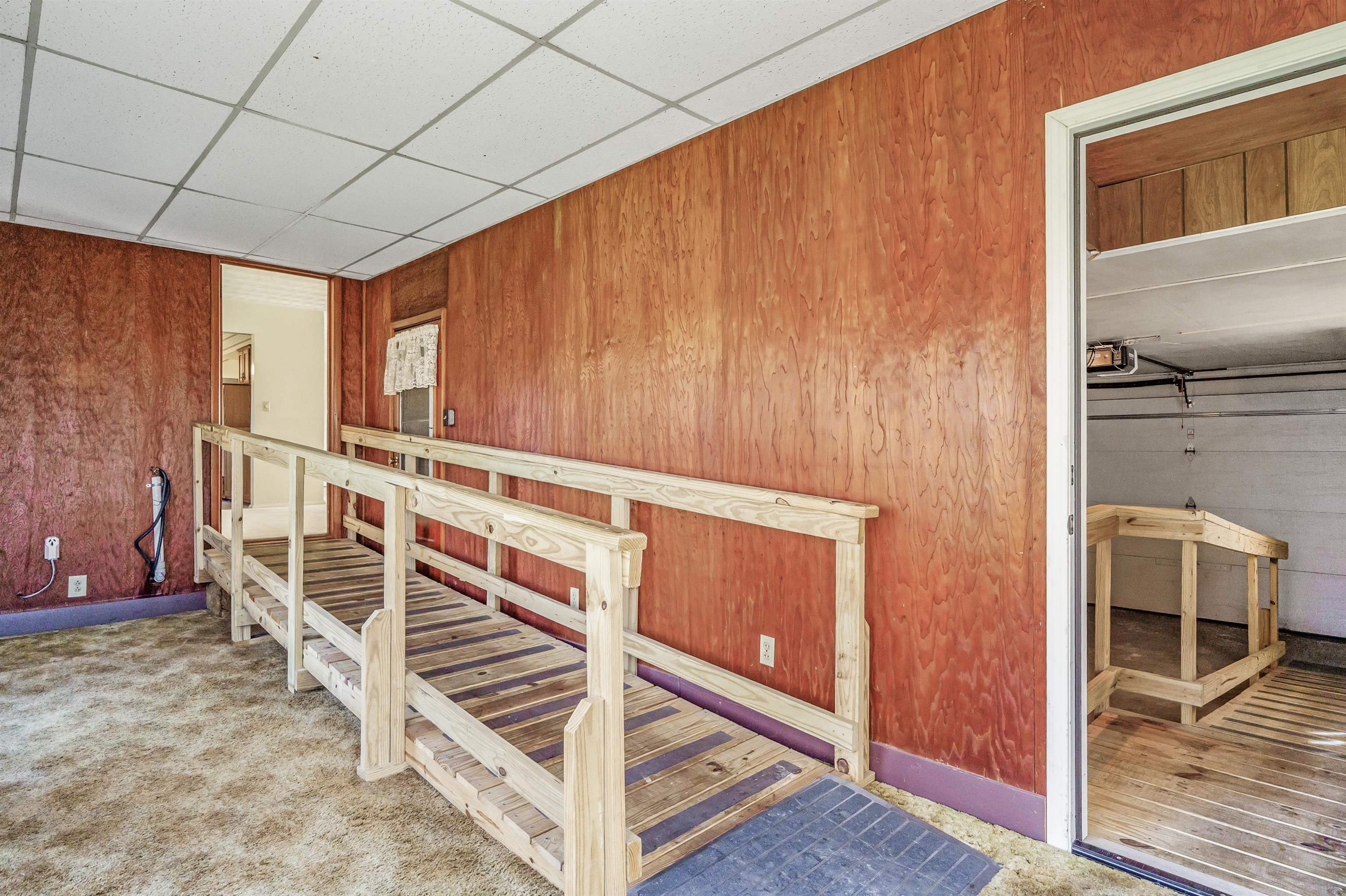 Stairs featuring wood walls, a drop ceiling, and carpet flooring