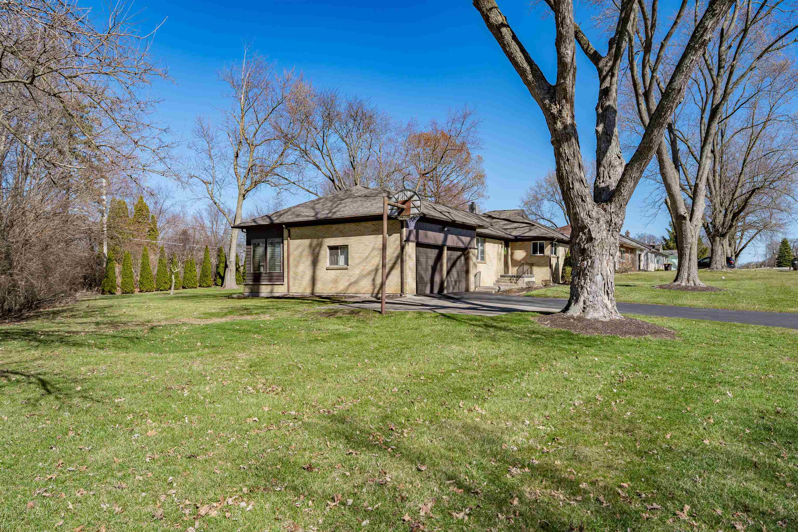 View of side of home with a yard, an attached garage, driveway, and stucco siding