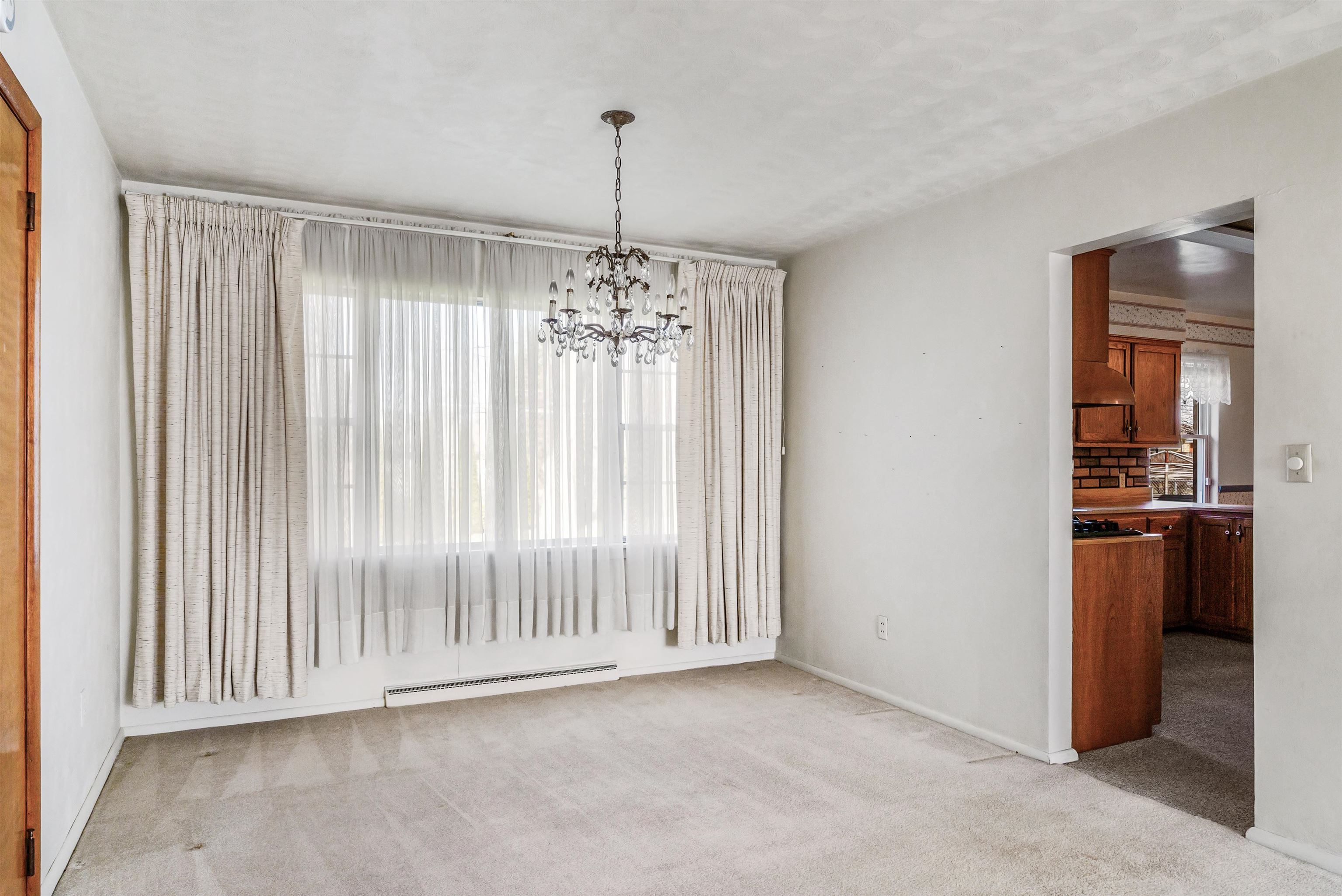 Unfurnished dining area featuring light colored carpet, suspended lighting, and baseboard heating