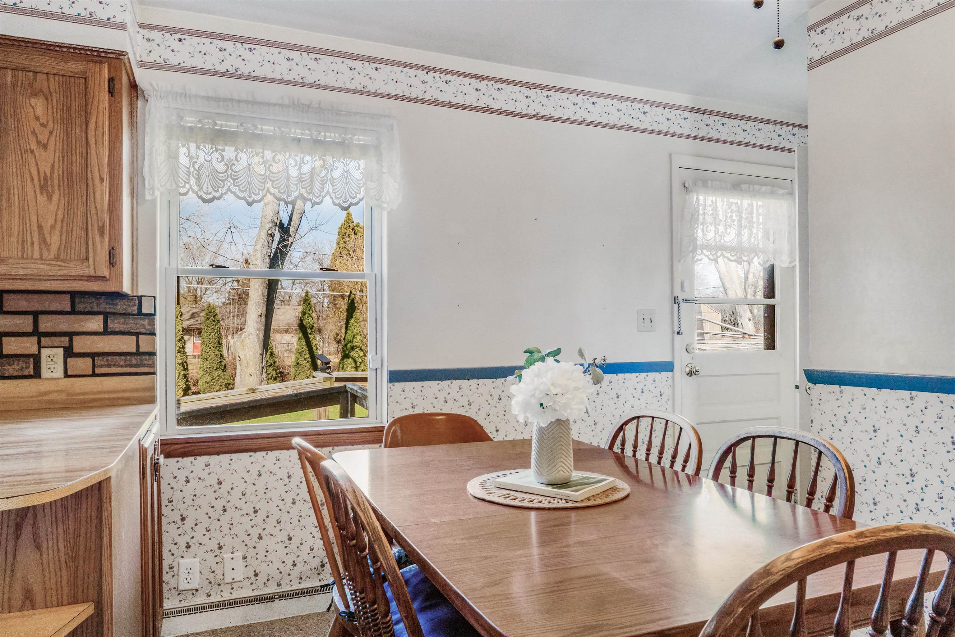 Dining area with wallpapered walls, a baseboard radiator, and wainscoting