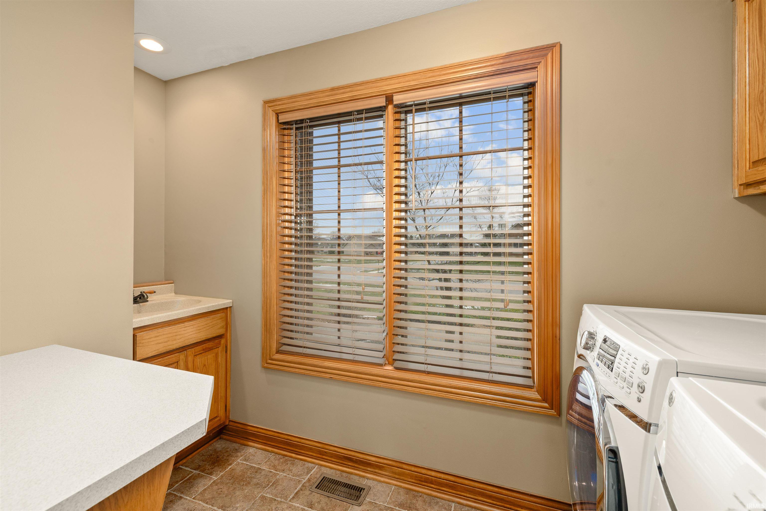Laundry area featuring washer and clothes dryer, cabinet space, light stone finish flooring, and recessed lighting
