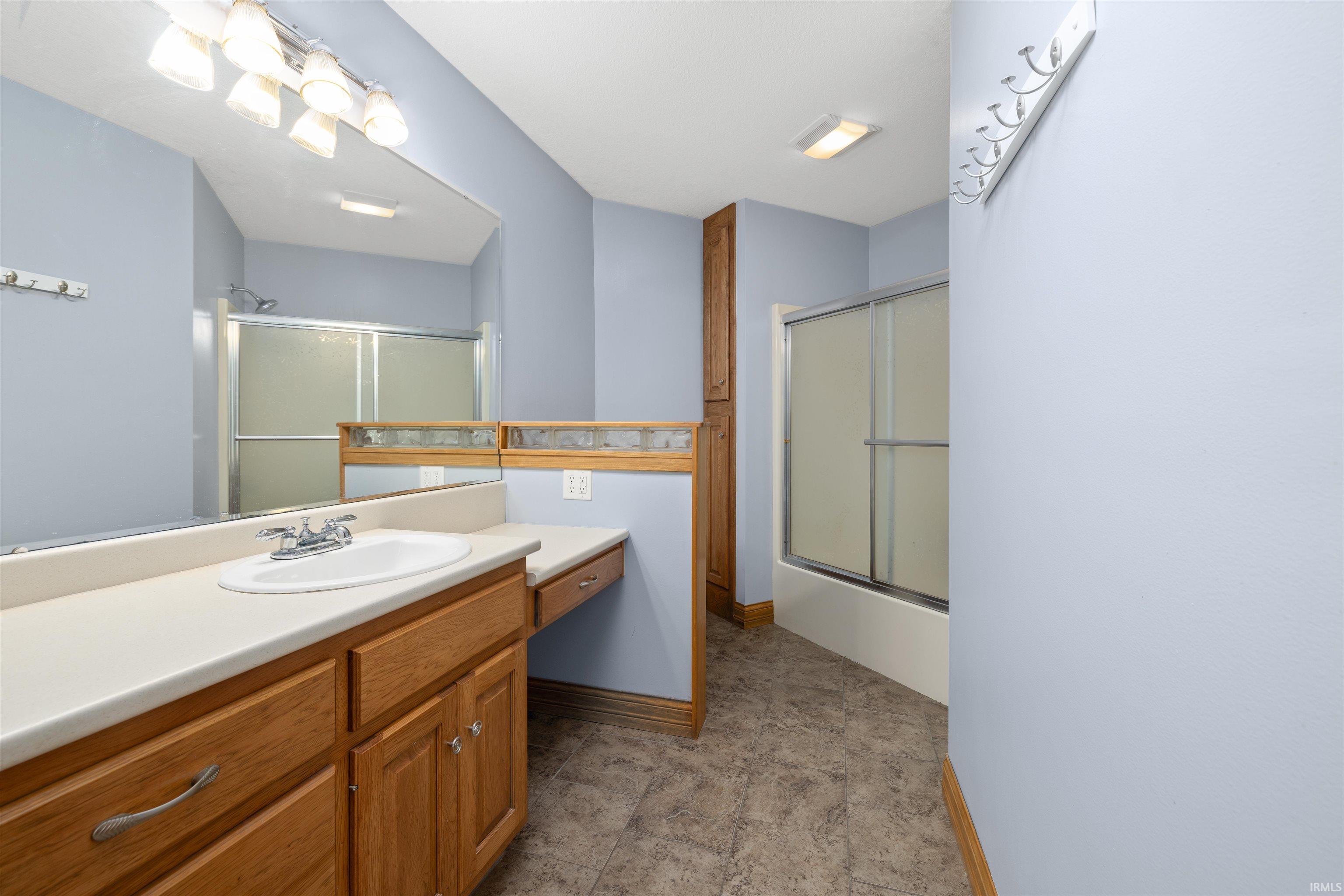 Bathroom with vanity and combined bath / shower with glass door