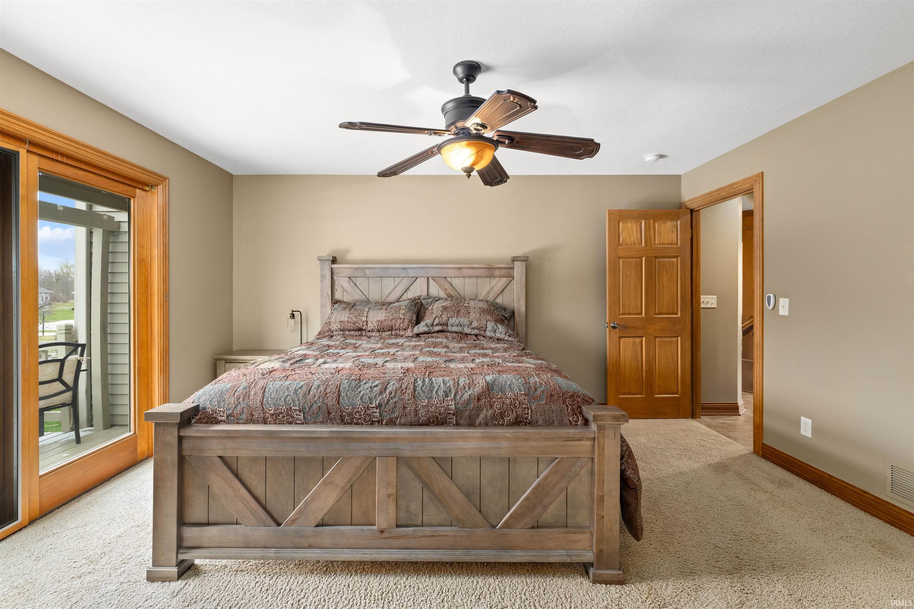 Carpeted bedroom with ceiling fan and access to outside