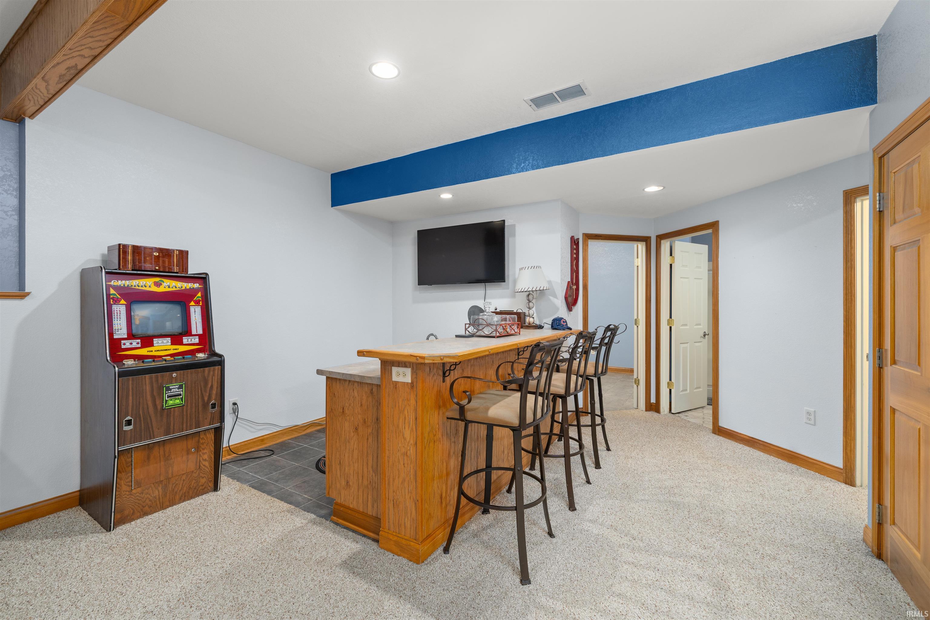 Indoor wet bar with light carpet, recessed lighting, light countertops, and wood finish cabinetry