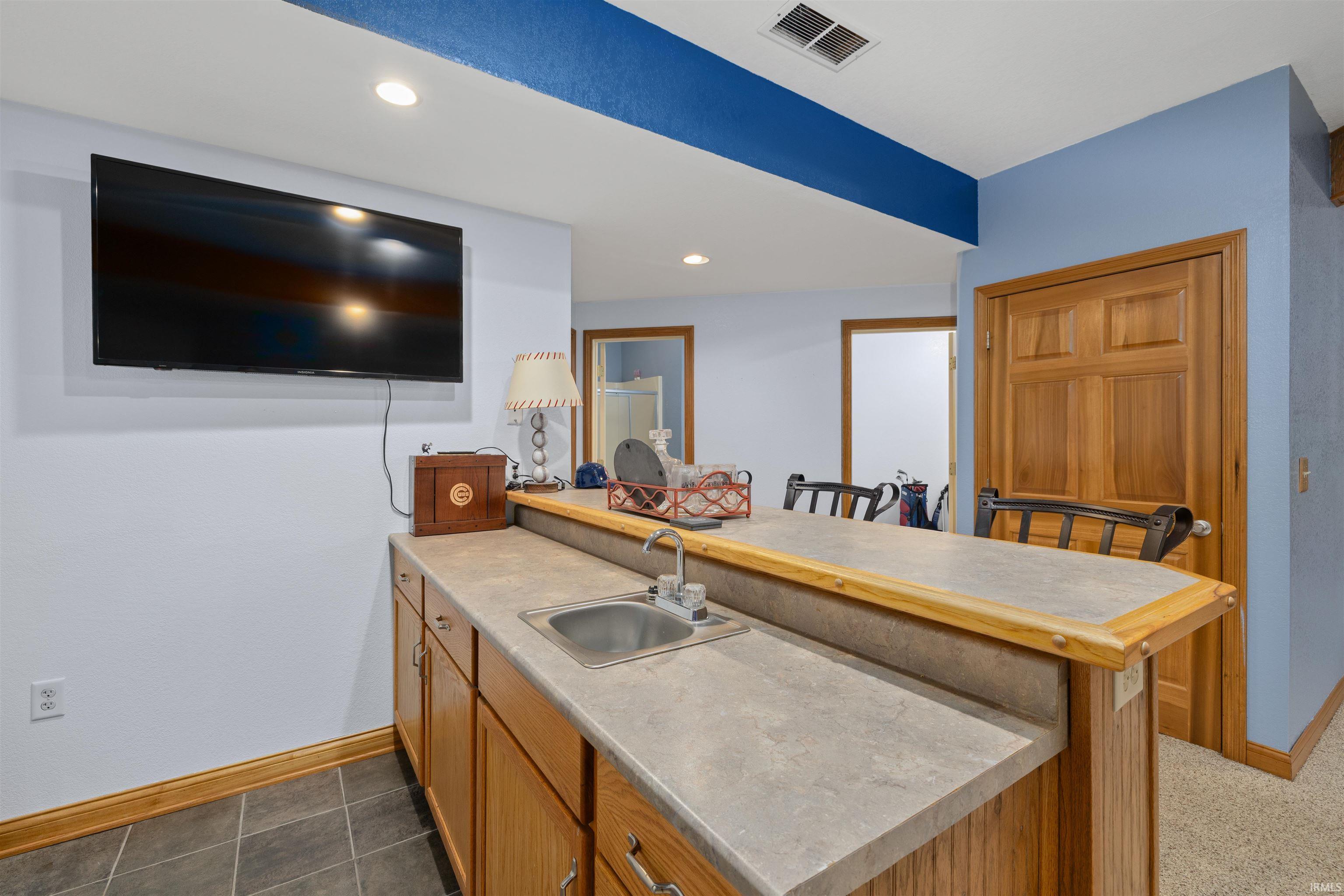 Kitchen featuring a peninsula, light countertops, recessed lighting, wood finish cabinets, and a kitchen bar