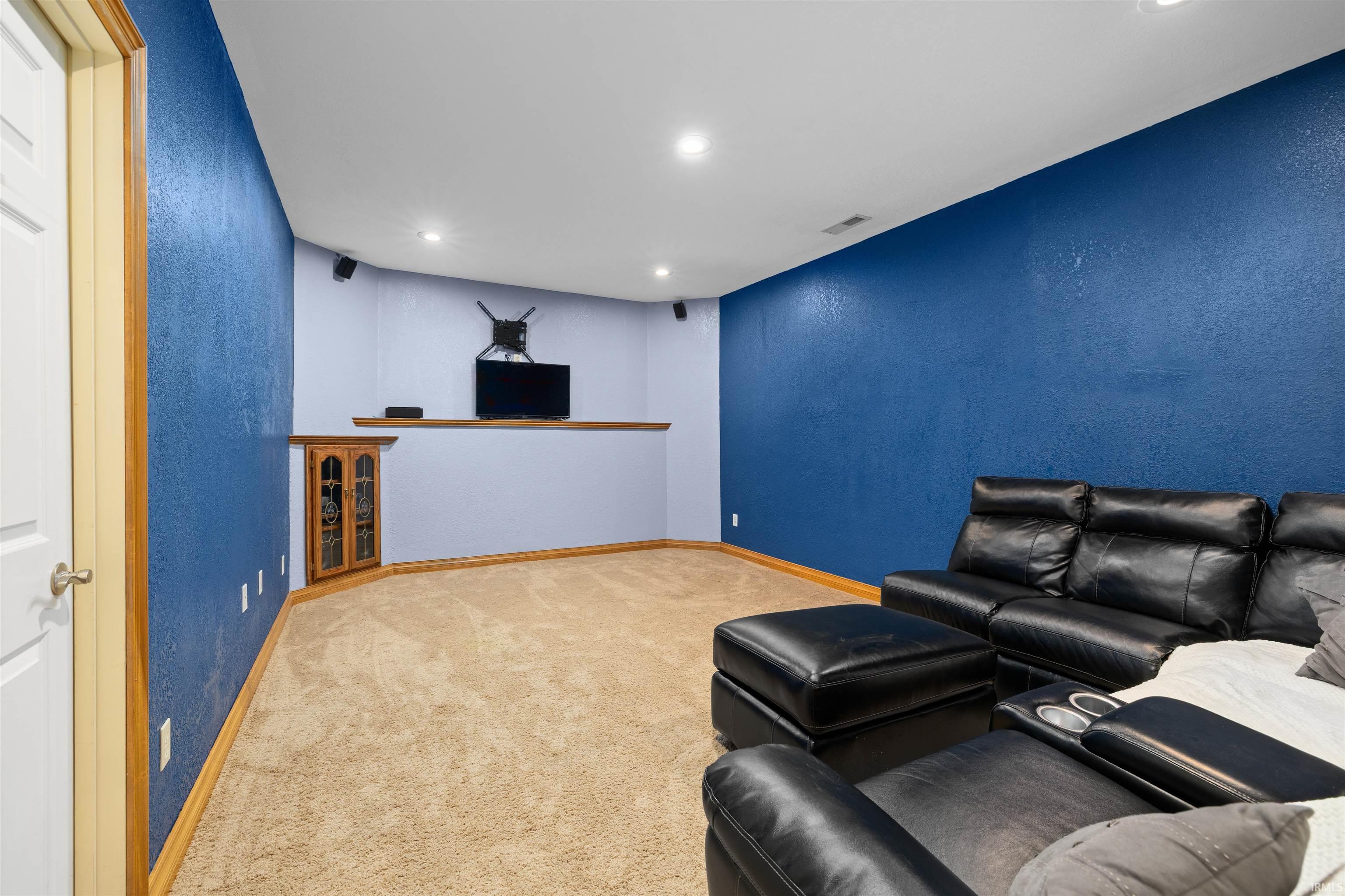 Living area with a textured wall, carpet floors, and recessed lighting