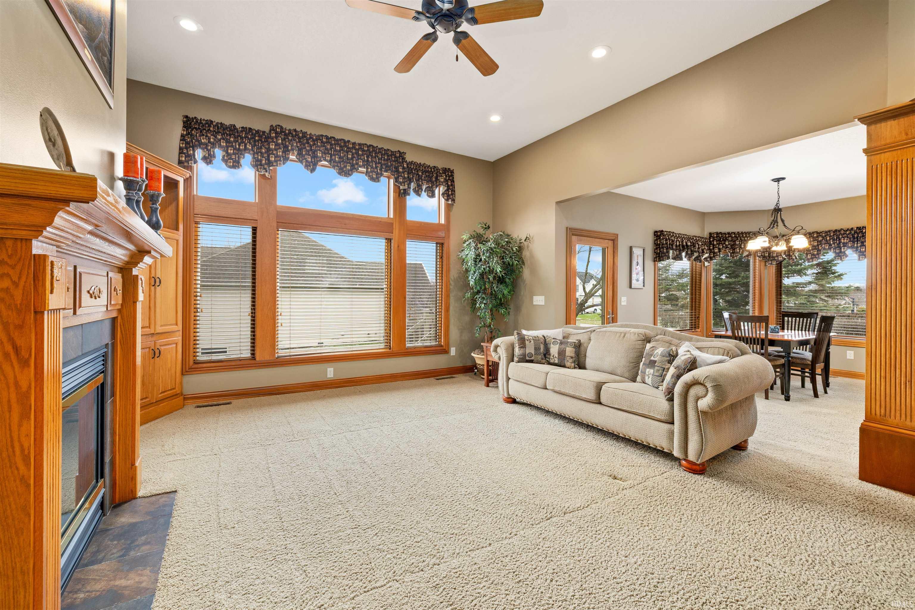 Living room featuring ceiling fan, light carpet, hanging lights, and healthy amount of natural light