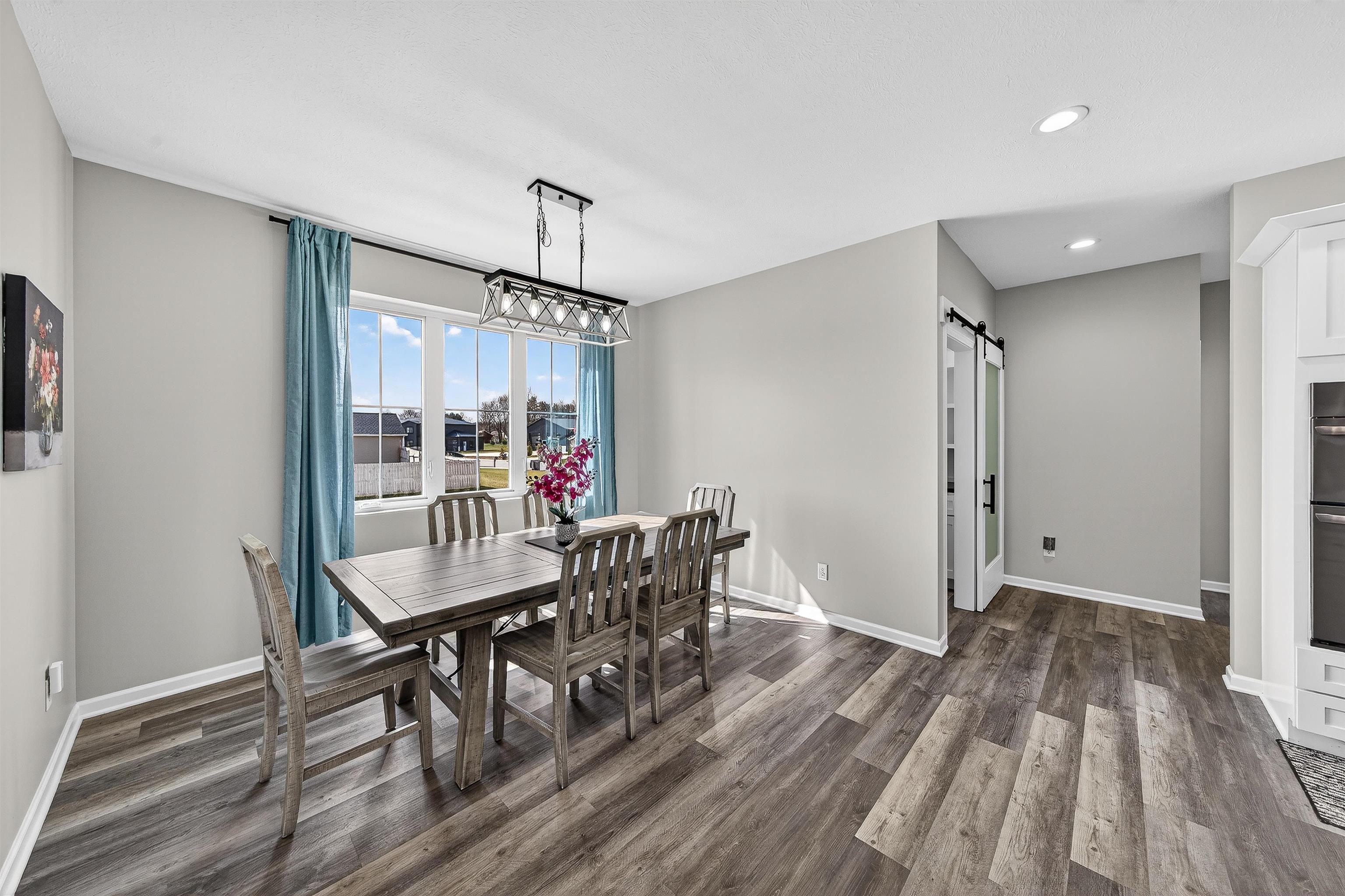 Dining room with a barn door, dark wood finished floors, and recessed lighting