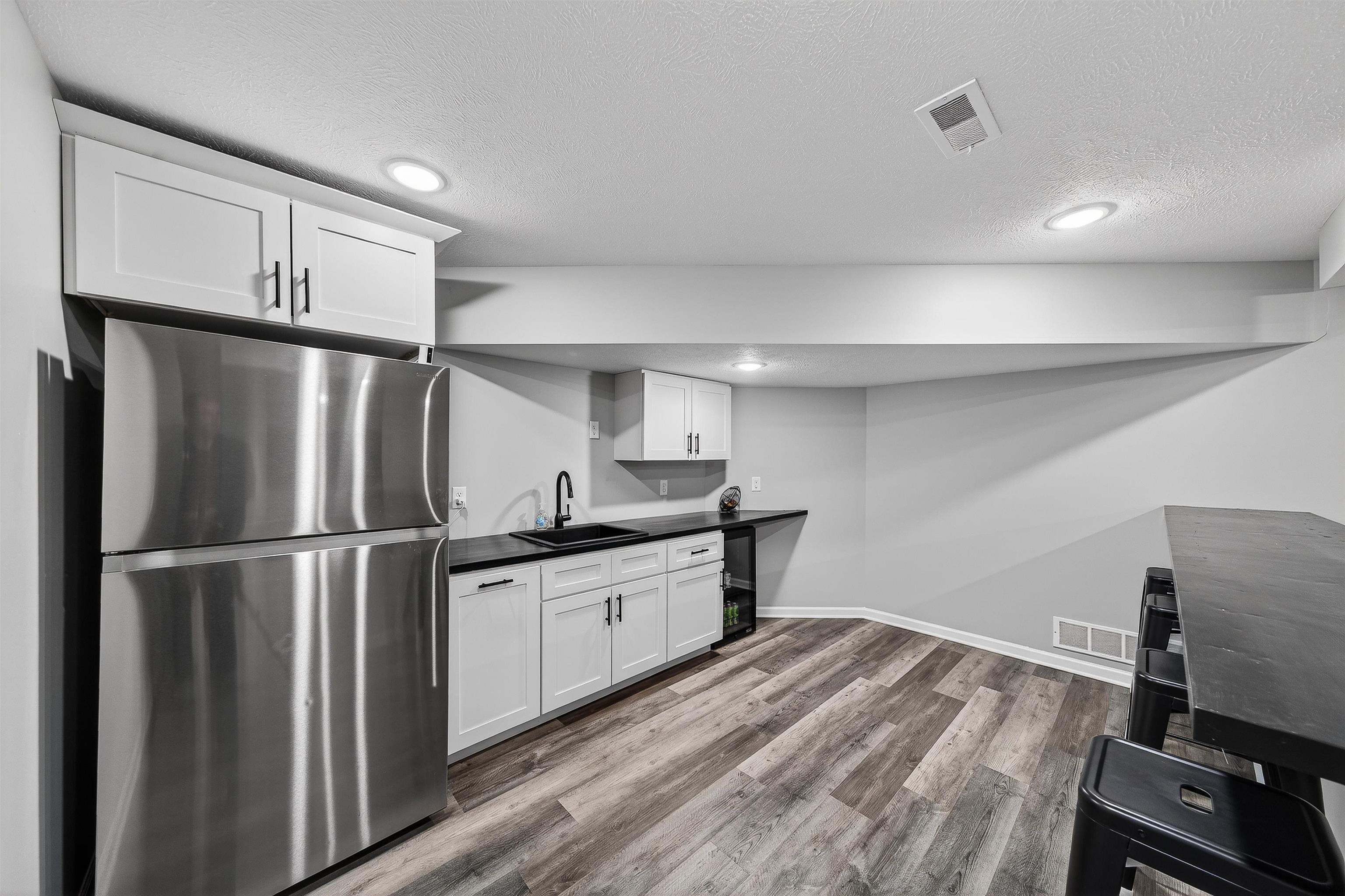 Kitchen featuring freestanding refrigerator, dark countertops, white cabinetry, light wood finished floors, and recessed lighting