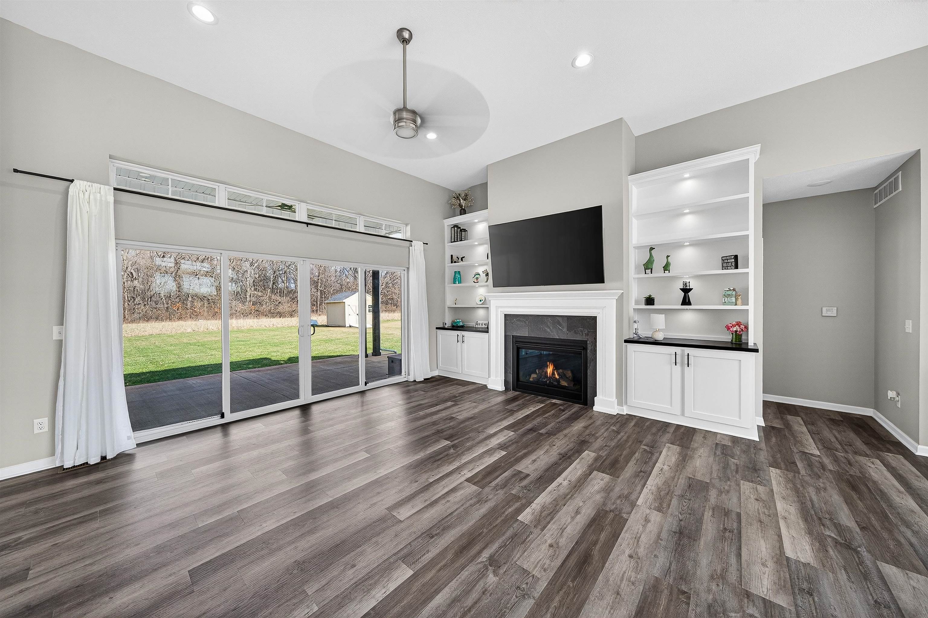 Unfurnished living room with a high end fireplace, a ceiling fan, dark wood-style flooring, and recessed lighting