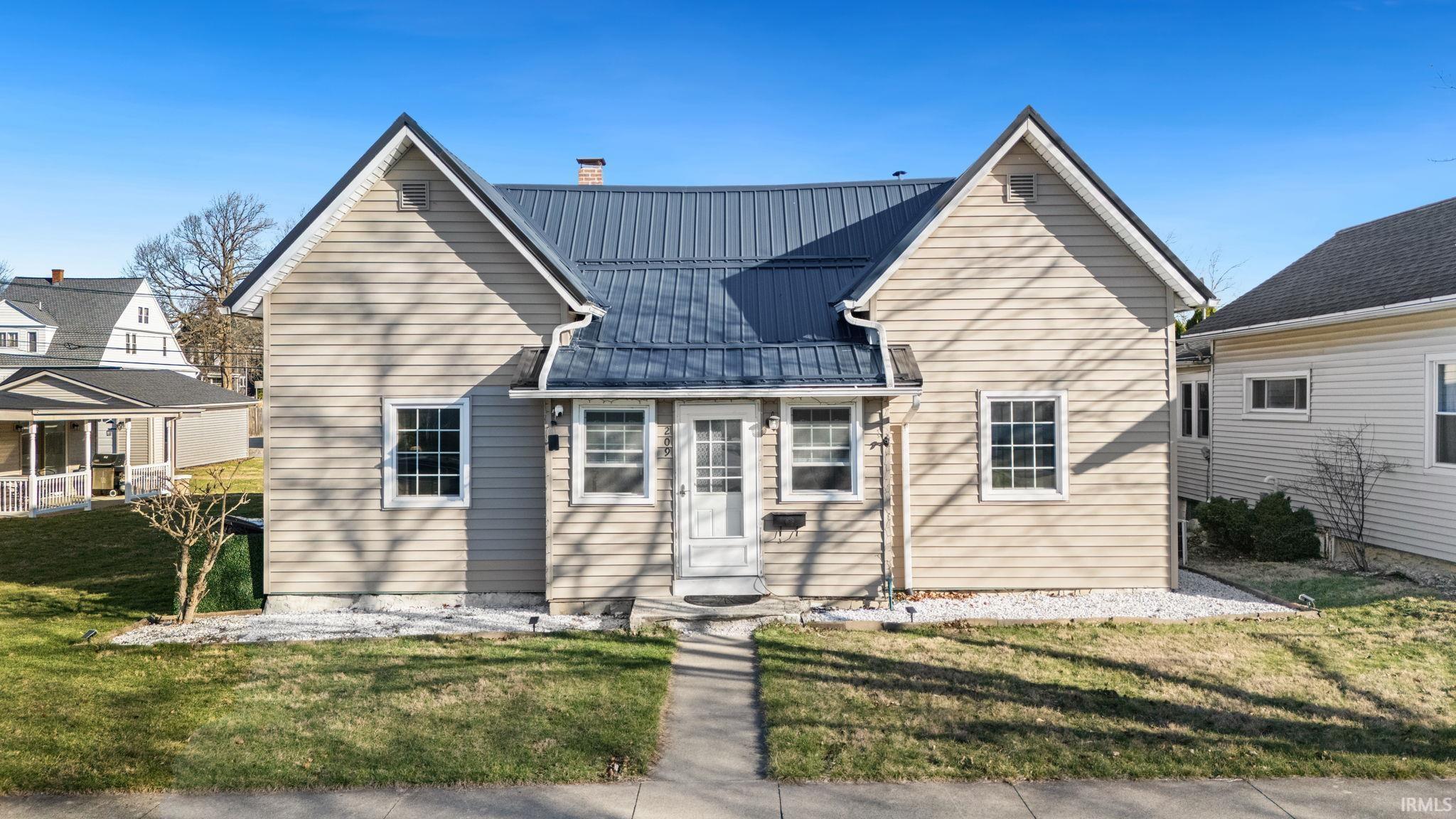 View of front of home with a front yard, a metal roof, and a chimney