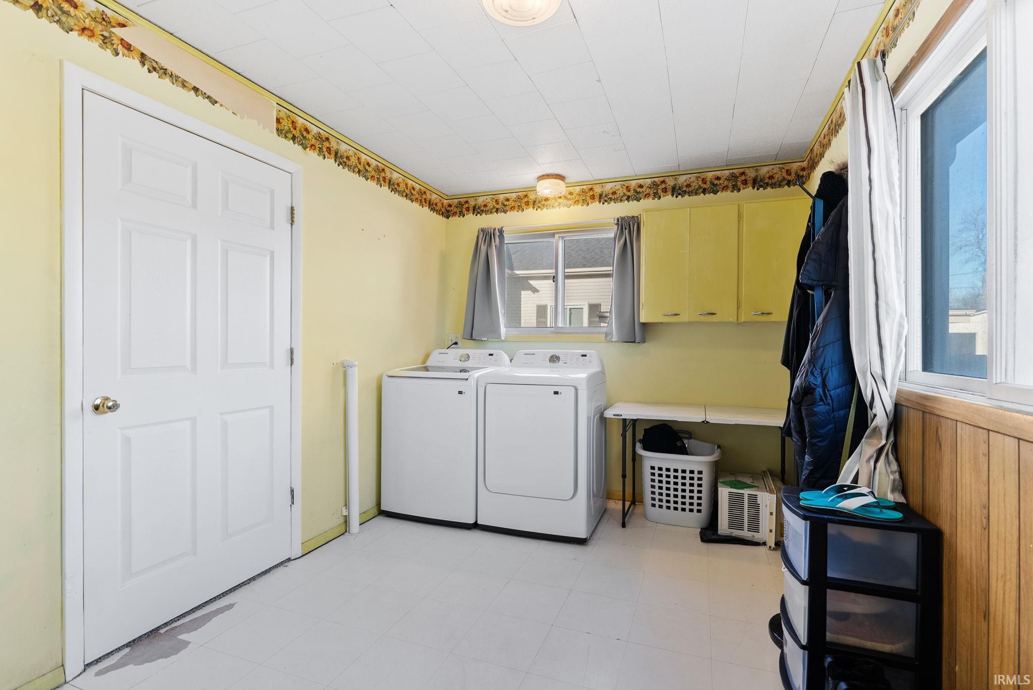 Laundry area featuring light flooring, washer and clothes dryer, and cabinet space