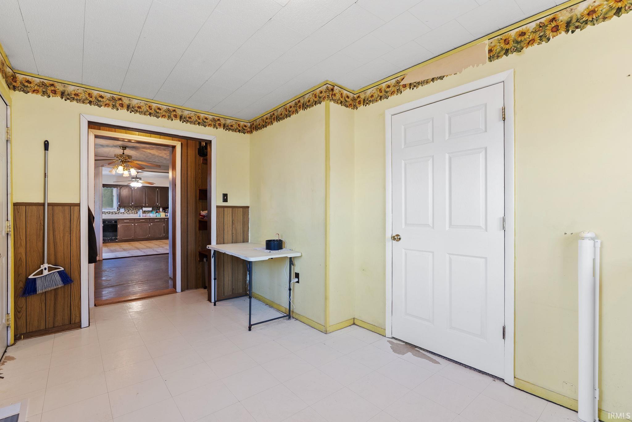 Office area with light floors, a ceiling fan, and a wainscoted wall