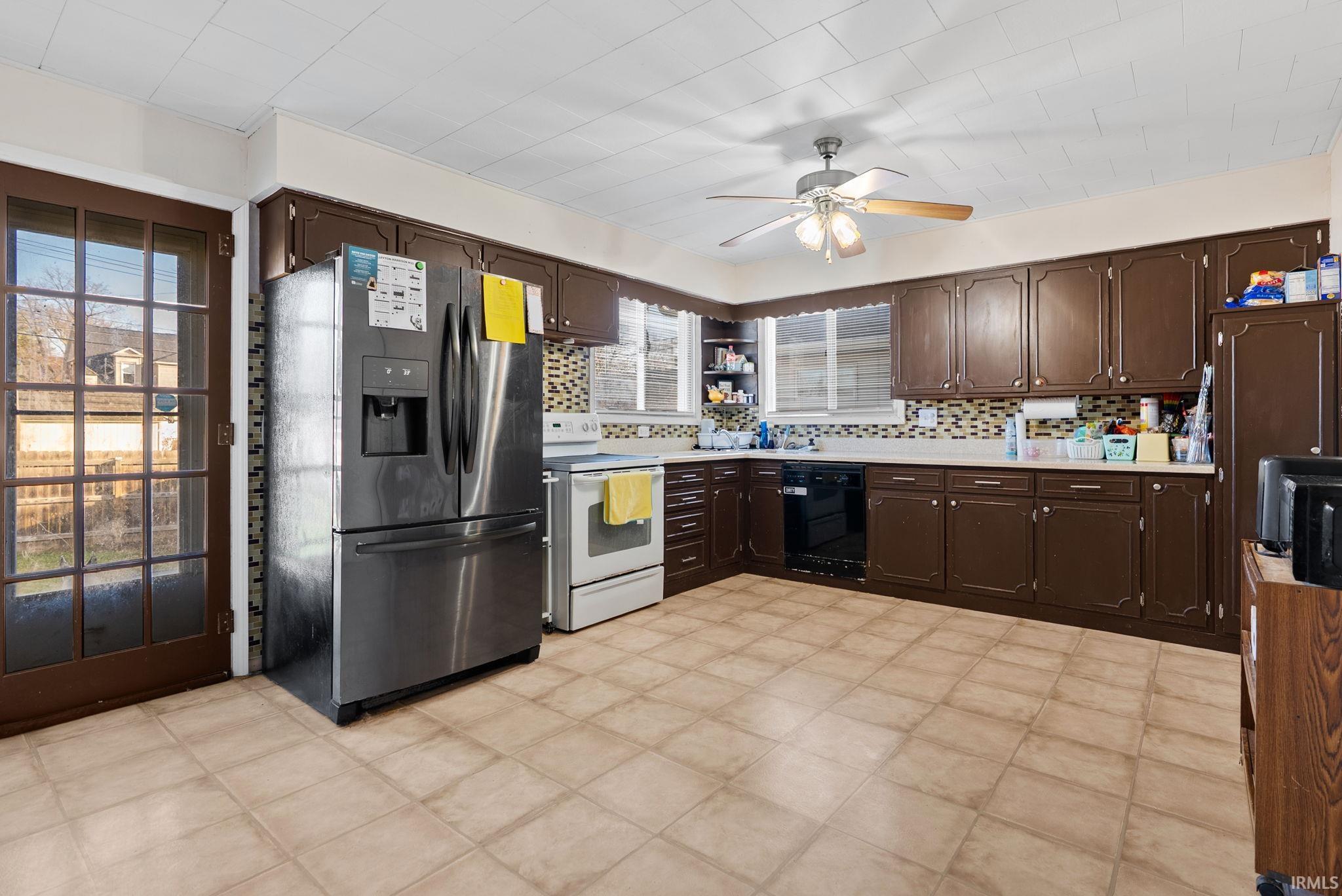 Kitchen with dark wood finish cabinets, stainless steel refrigerator with ice dispenser, white electric range, and a ceiling fan