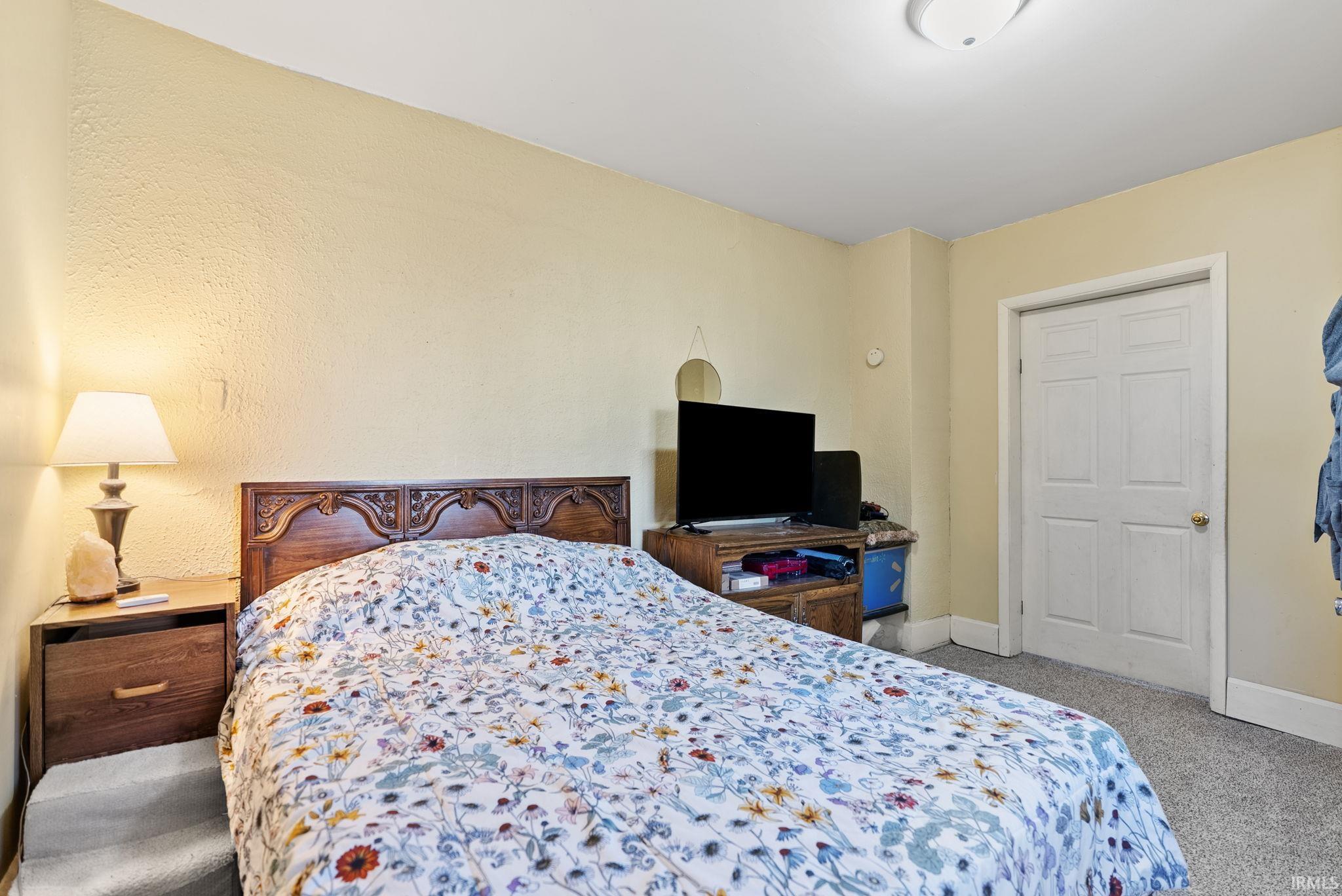 Bedroom with light colored carpet and baseboards